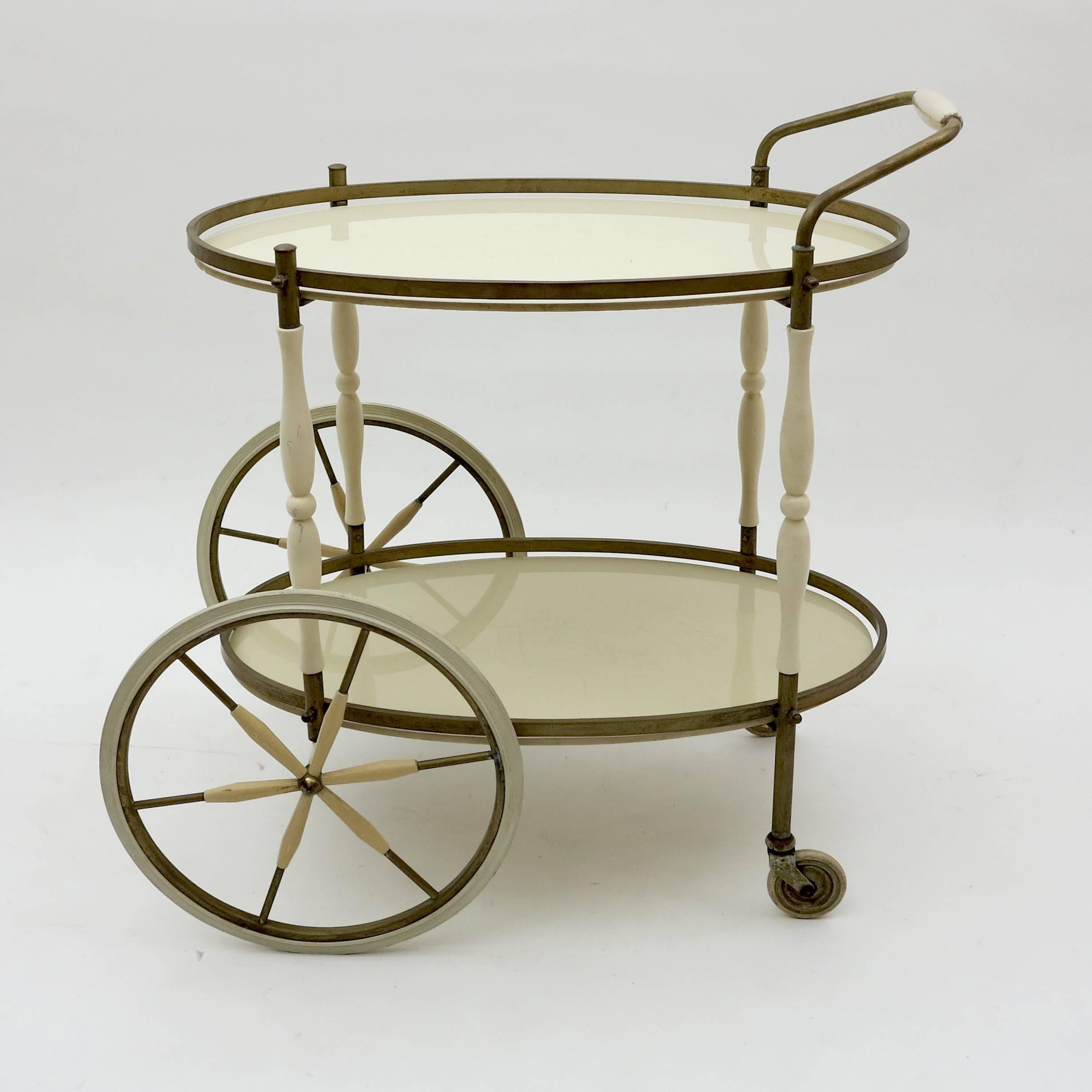 This unique and elegant trolley has two white glass shelves on a bronze and wood structure, with a pair of large wheels and two small balancing wheels at the back for easy movement. Perfect for serving in a party!