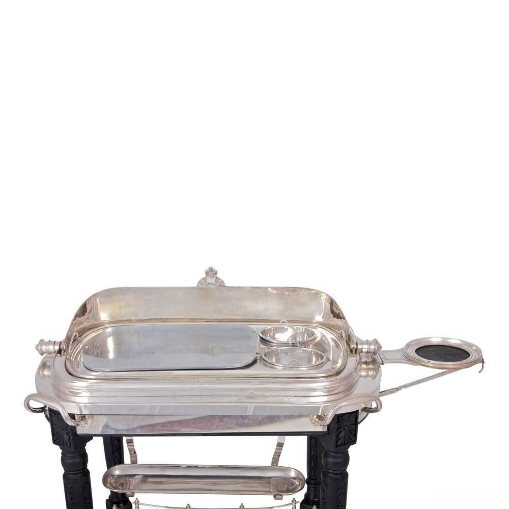 Silver plated roll topped carving trolley with carved black wood frame. Complete with burners, hot water compartment, sauce pots etc.
Measures: Approximately 41