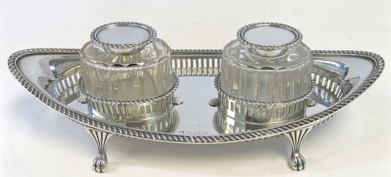 Adams style, sterling silver, two bottle inkstand. The oval pierced gallery frame with gadroon bordered rim, stands on four elegant paw feet. The oval bottles are fluted glass with gadroon rim sterling silver hinged covers and sterling silver