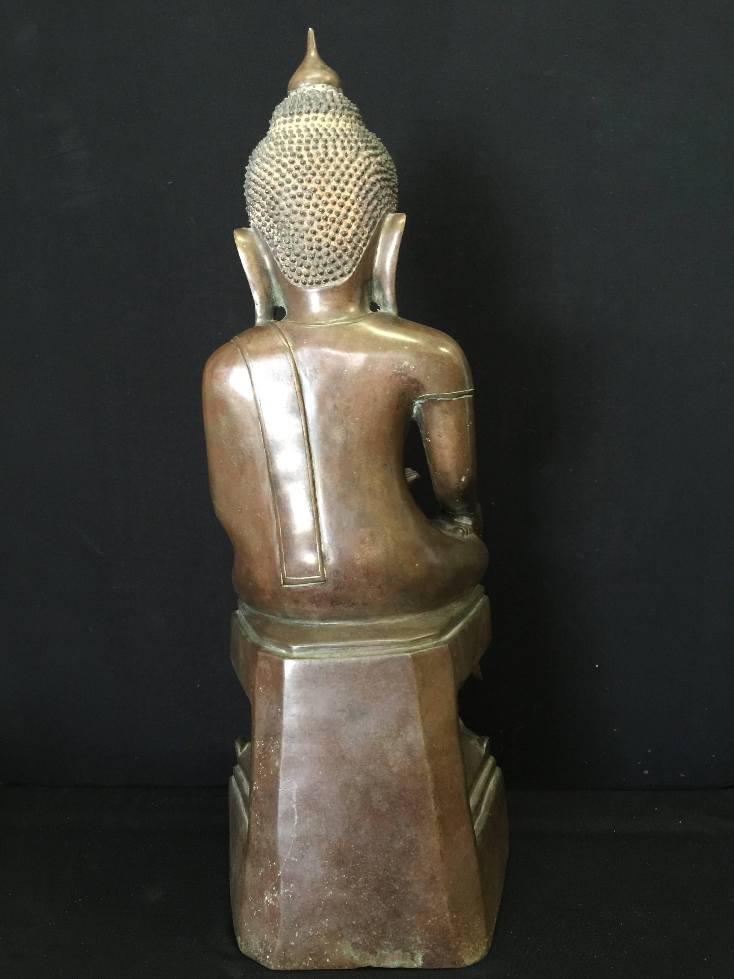 Sitting Buddha on a large throne. The classical Awa Buddha has a dark brown patina and is in excellent condition.