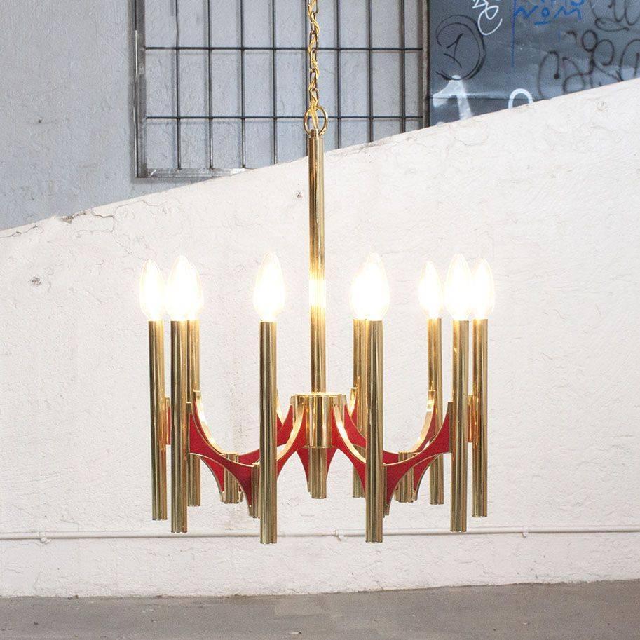 Marked Gaetano Sciolari twelve-arm chandelier in polished brass.
Brass tubes are connected with red buttresses to give light for 12 bulbs.

There are two chandeliers available. 

