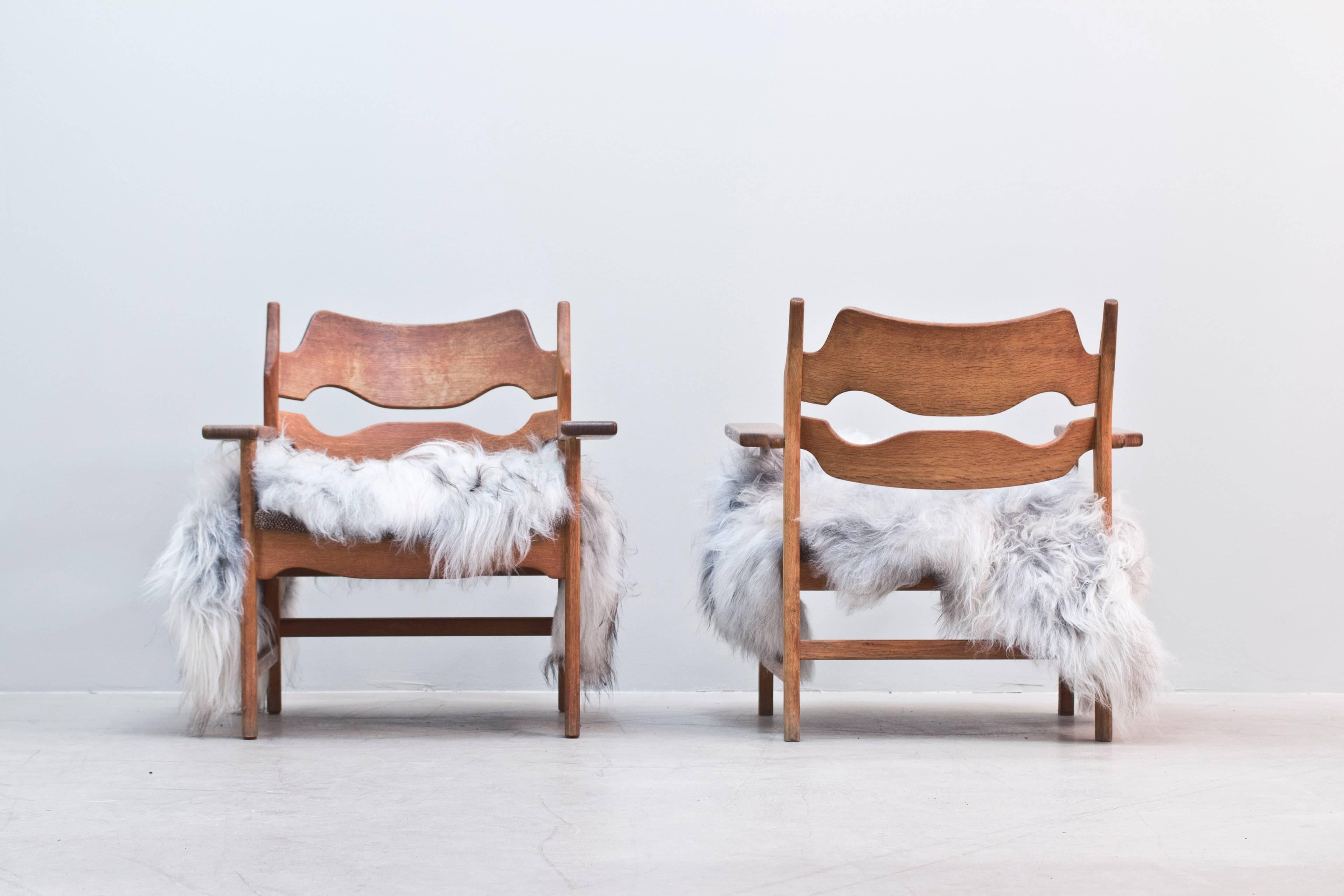 Pair of Danish armchairs in oak frame with original upholstery designed by Henning Kjaernulf. Covered in Icelandic sheepskin (removable). 

Please contact us for ideas of new upholstery if requested.