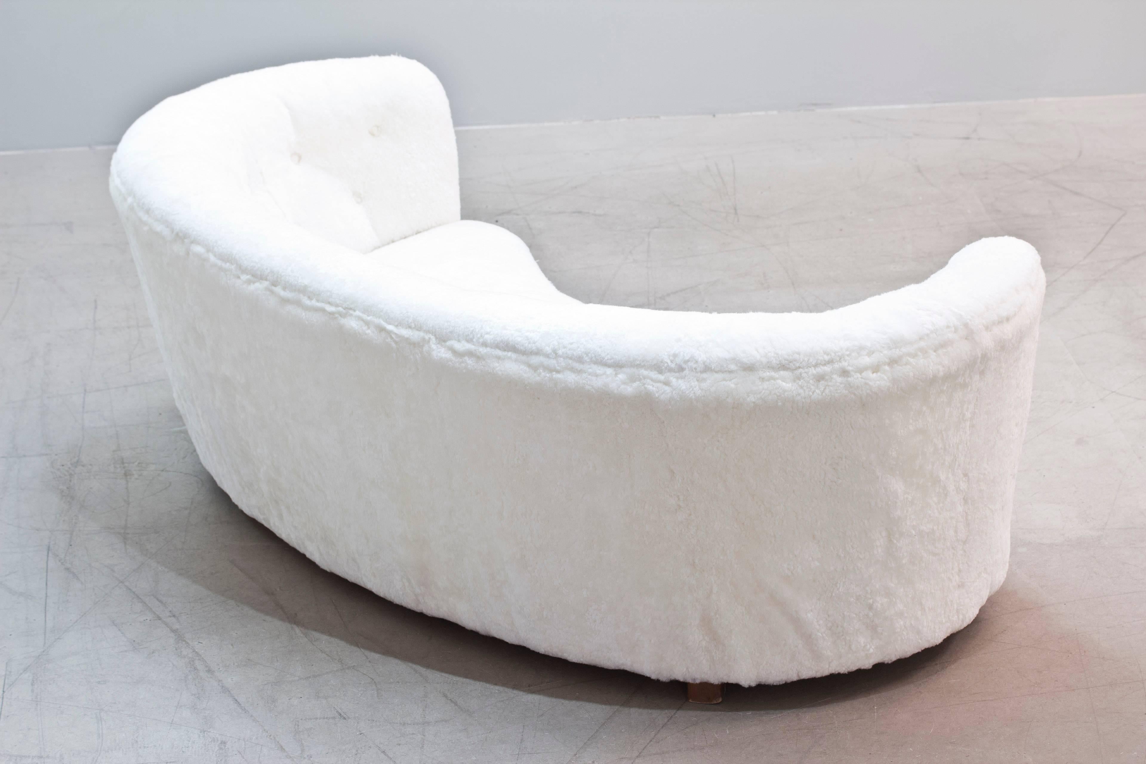 Swedish Modern curved sofa newly upholstered in white sheepskin with wooden structure and feet, circa 1930s.