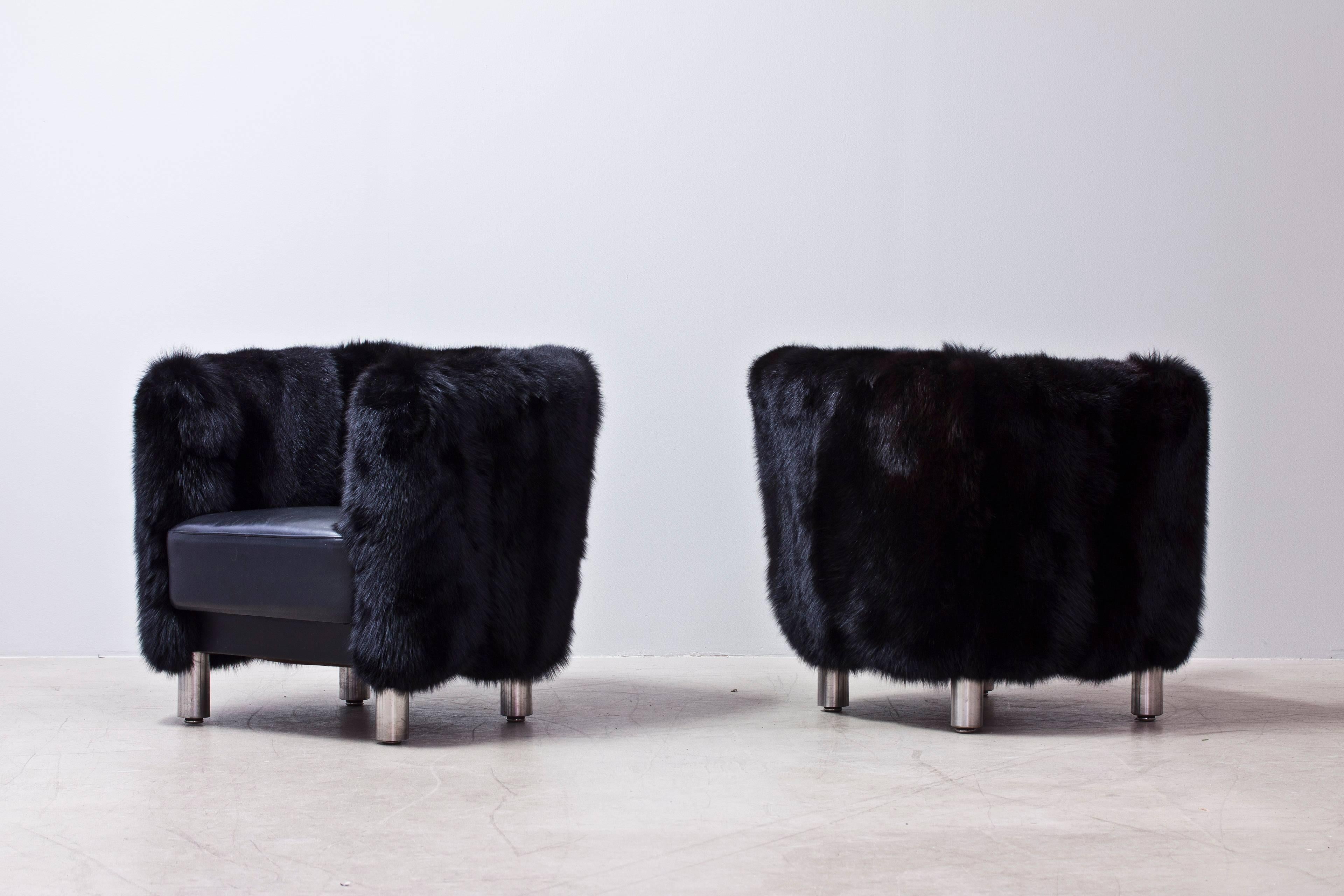 Pair of armchairs in upholstered black fur on armrests and leather seat with chrome leg base.