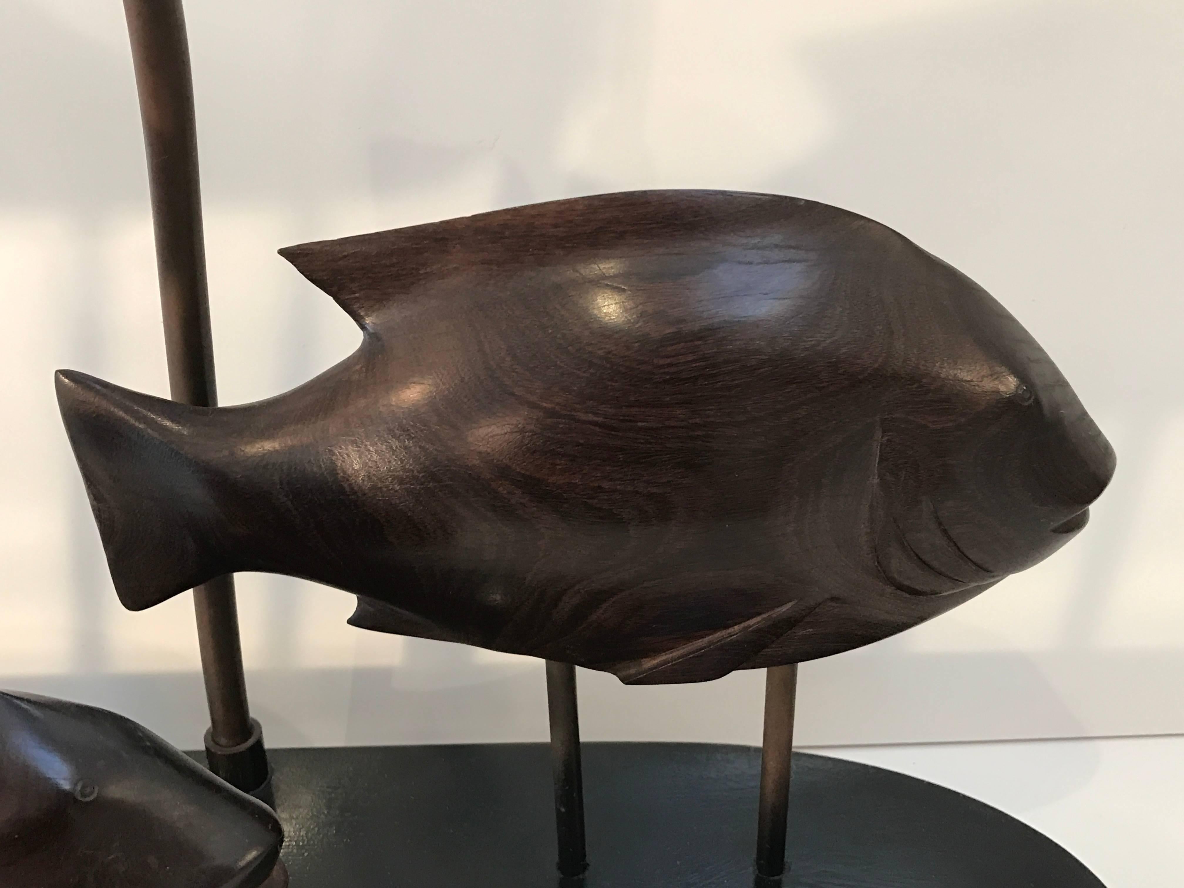French Modern School of Fish Lamp, three well carved rosewood graduating (measures: largest 11" W, medium 10" W, small 7.5" W) fish museum mounted on an oval ebonized base. Fitted with two bulbs. Shade is not included, for display