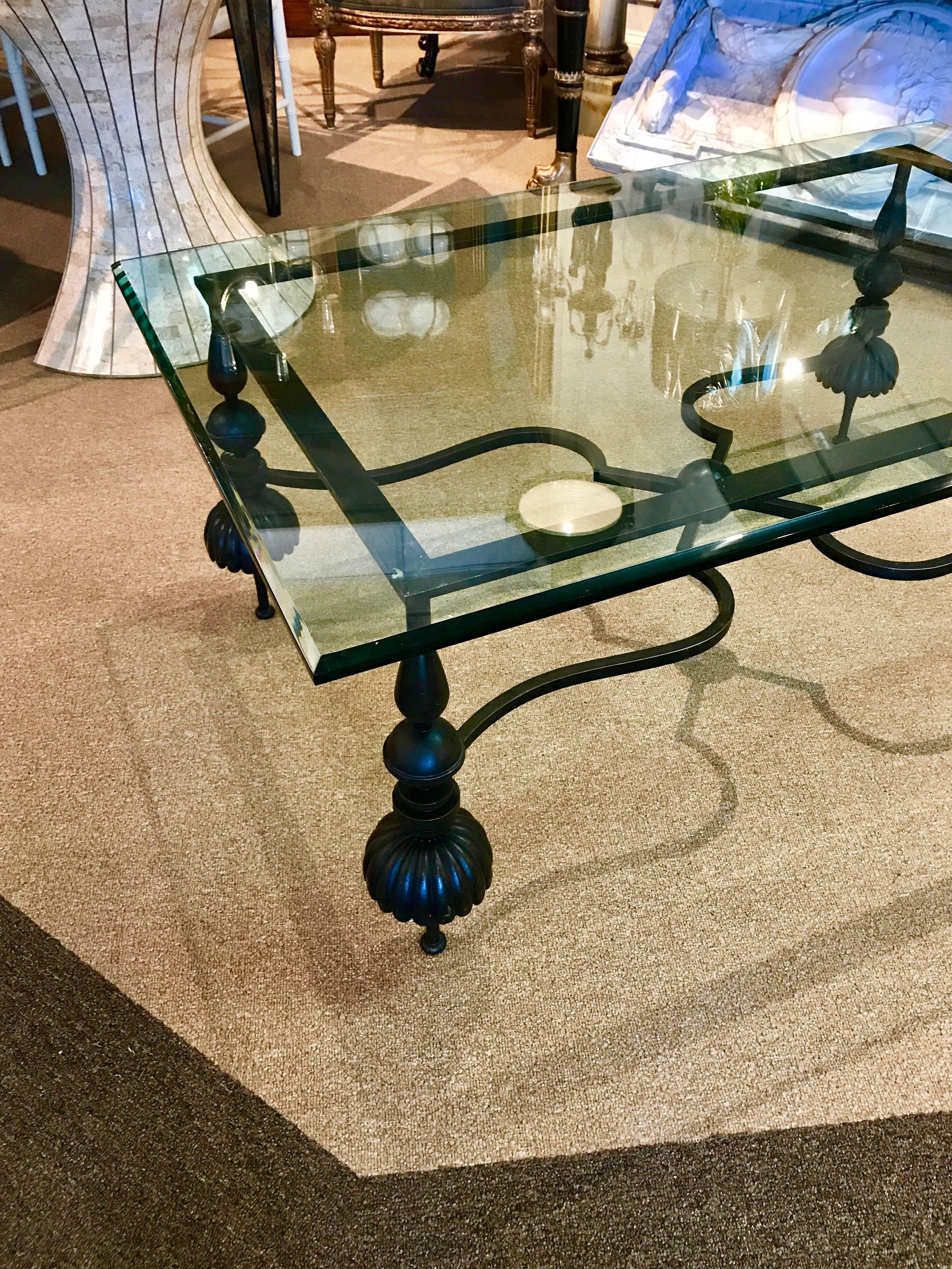 Beautiful wrought gun metal and beveled glass coffee table, with rectangular 32 inches deep by 49 inches wide glass top with beveled edge, raised 20 inches high on a stylized wrought gun metal base, with deep gray patinaed steel hues.