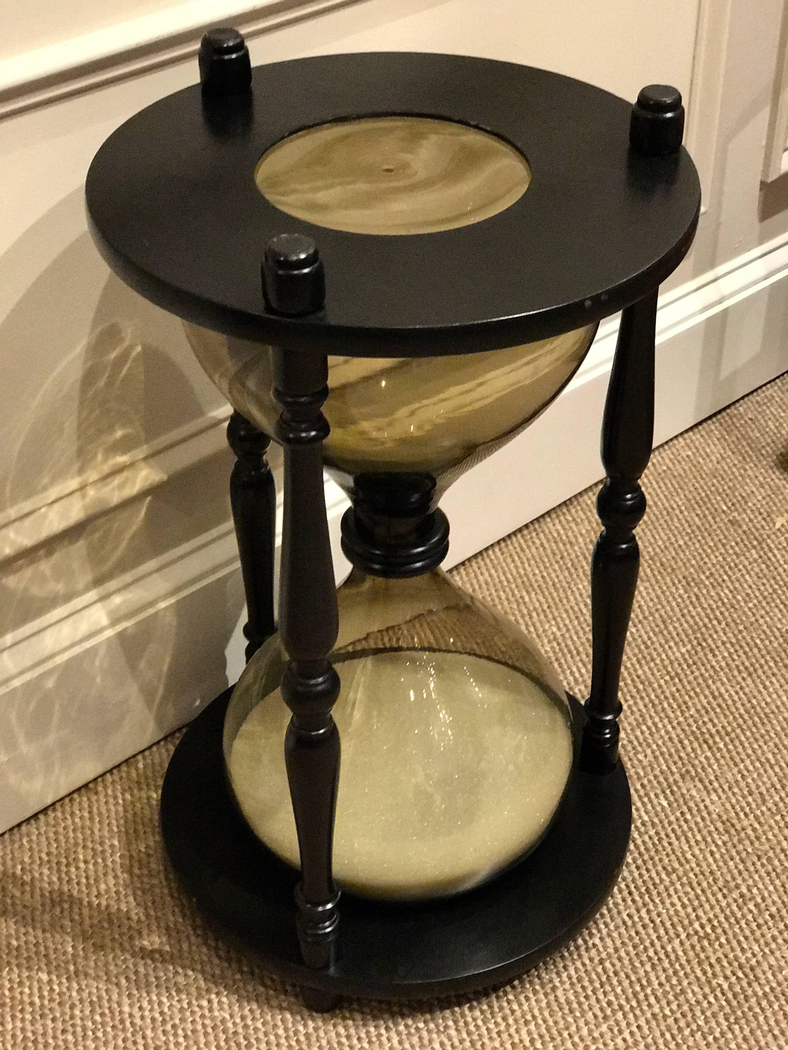 An oversized ebonized hourglass side table and functioning timepiece, when overturned one hour will pass. Finished on top and bottom. Fitted with a beautiful 20
