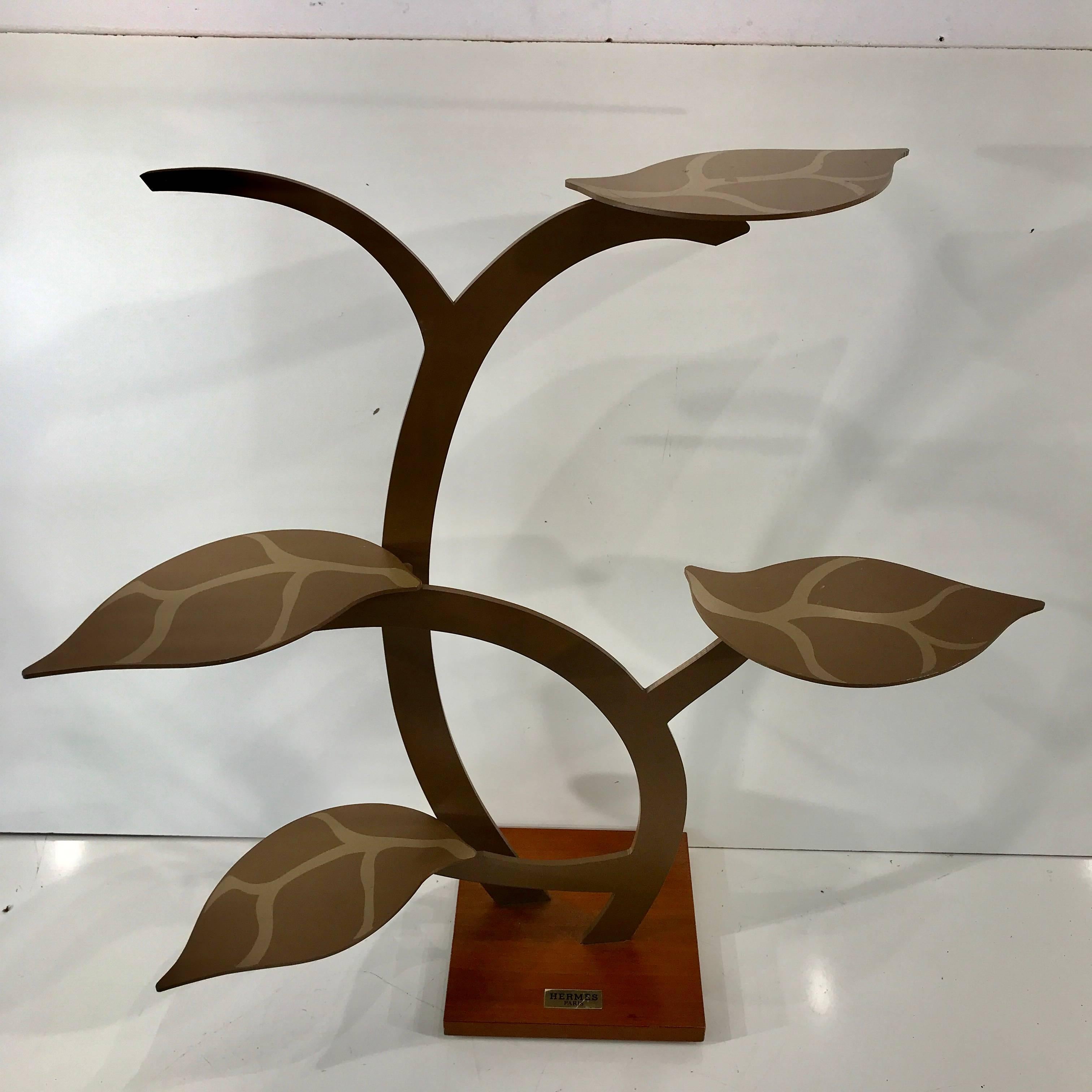 Vintage Hermes display stand, this remarkable tree is made of enameled and polychromed metal mounted on a square wood base. The leaves serve as display surfaces and are removable. Each leaf measures 8.5