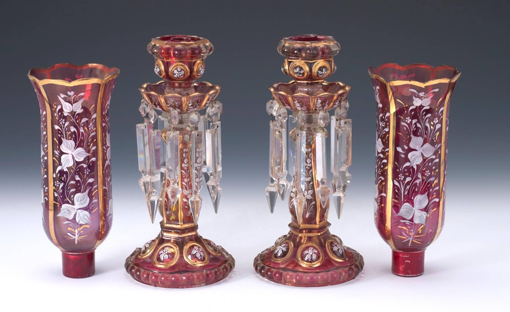 Pair of antique Baccarat enameled cranberry candlesticks, each one with enamel floral decoration and gilt highlights. Both have later cut semicircle indenture for cord and electrification if desired.

