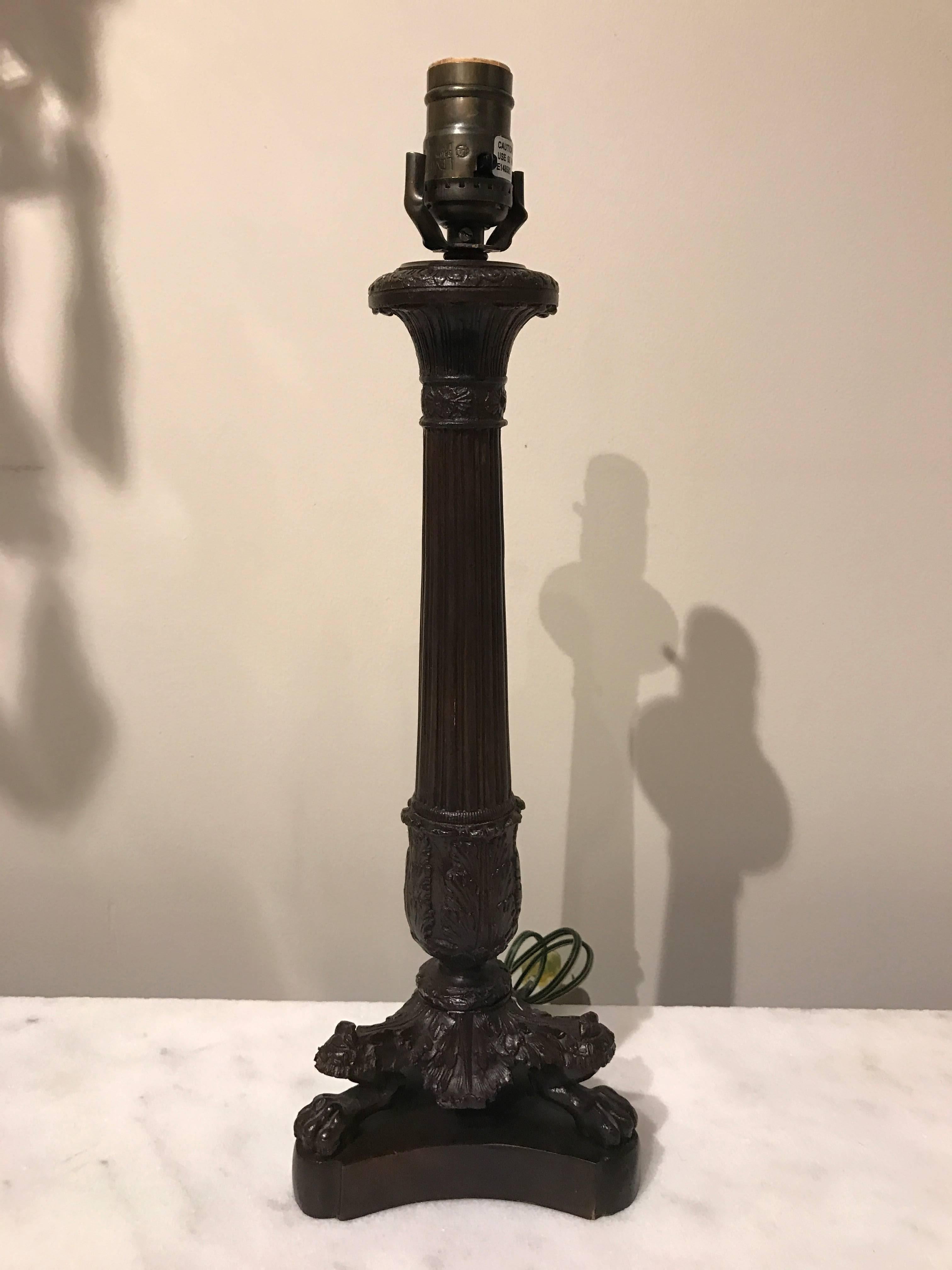 A pair of Empire Style bronze column candlestick lamps, each one of typical form raised on three paw feet.