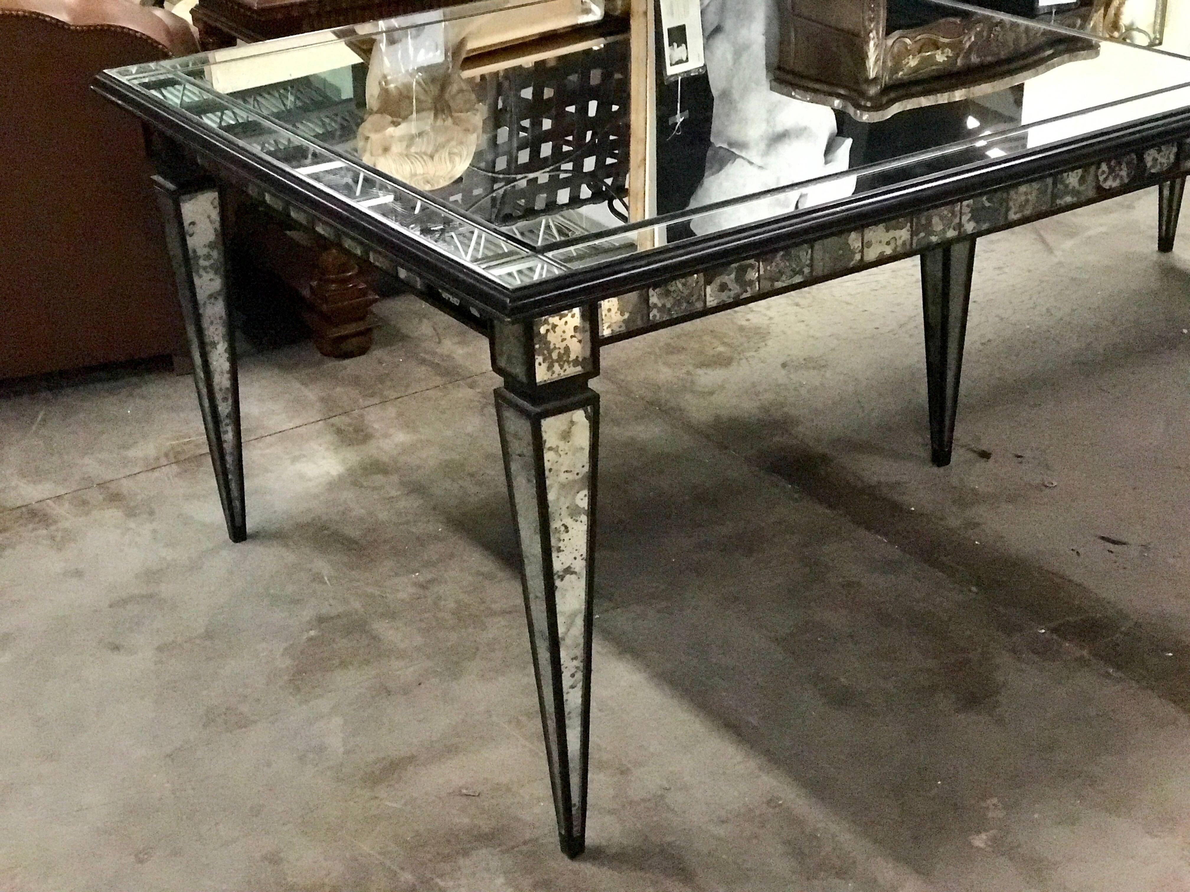Stunning Maison Jansen blackened wood mirrored dining room table, in two equal parts with middle support leg if desired. Fitted with clear mirror on the surface and intentionally distressed mirror on the legs.