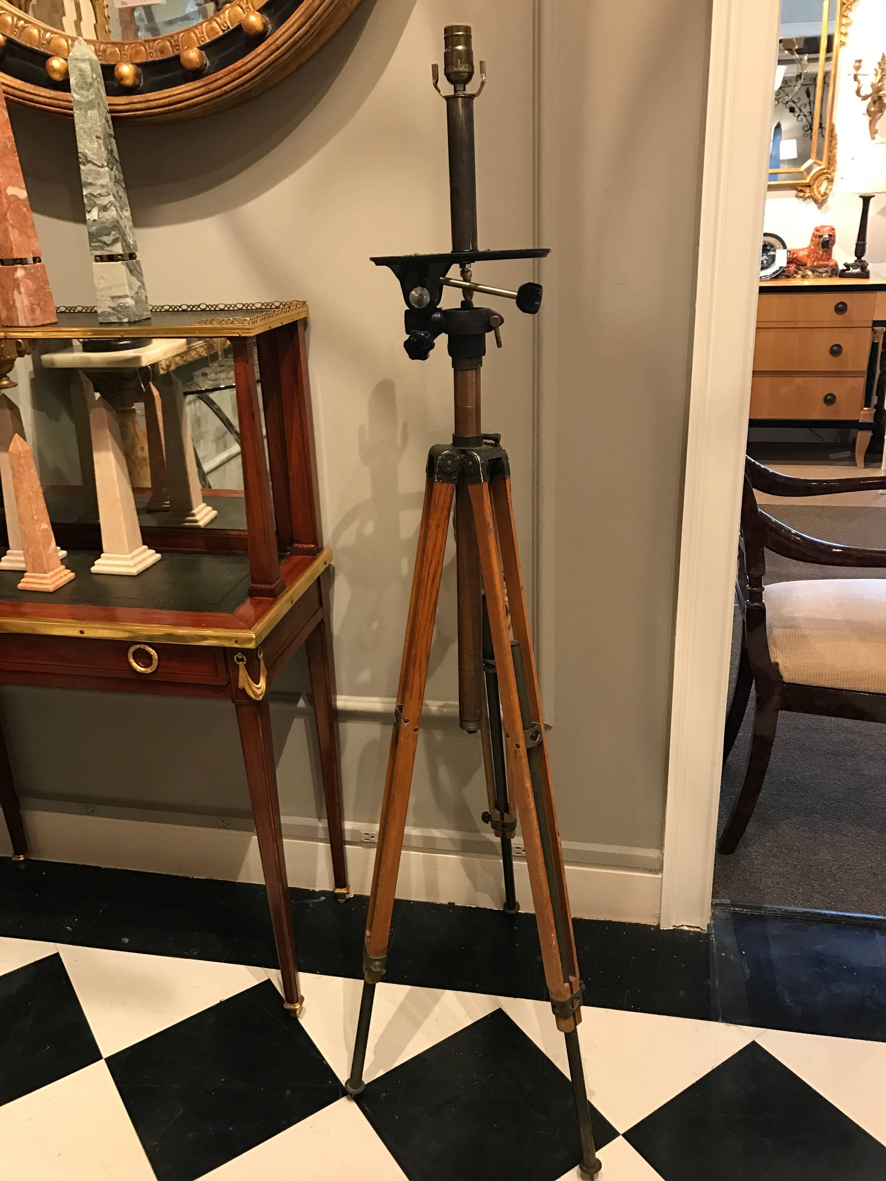 Antique movie camera tripod stand, now as a lamp, similar form as a surveyors tripod, made of carved maple and extendable brass legs. Complete with custom gilt and gun metal shade measuring 12
