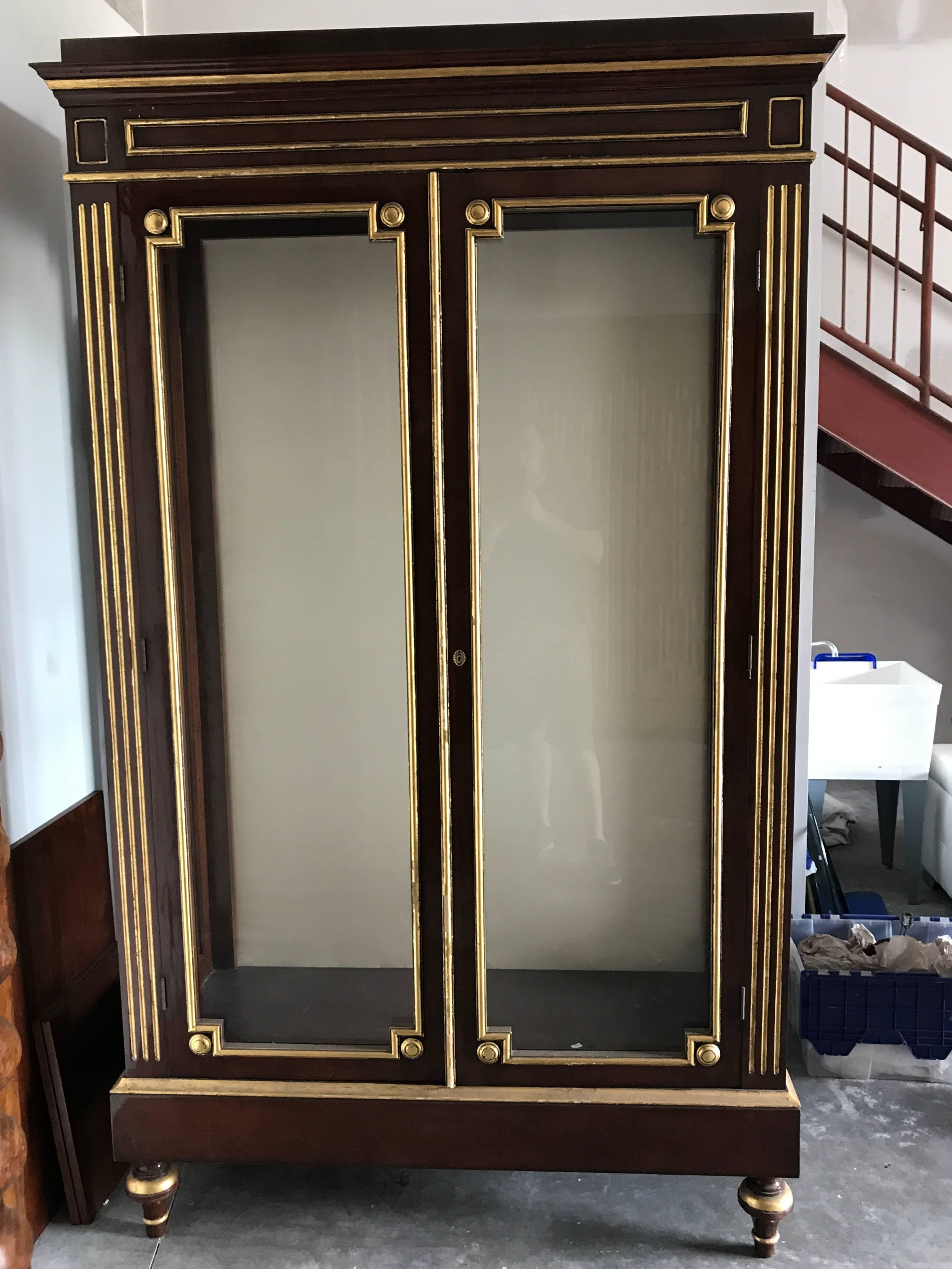 Large Napoleon III Style Vitrine, beautiful mahogany with gilt highlights, the case fitted with two large glass panel doors and sides, raised on toupee feet. This item is a floor room sample. Shown without shelves, will provide three glass shelves