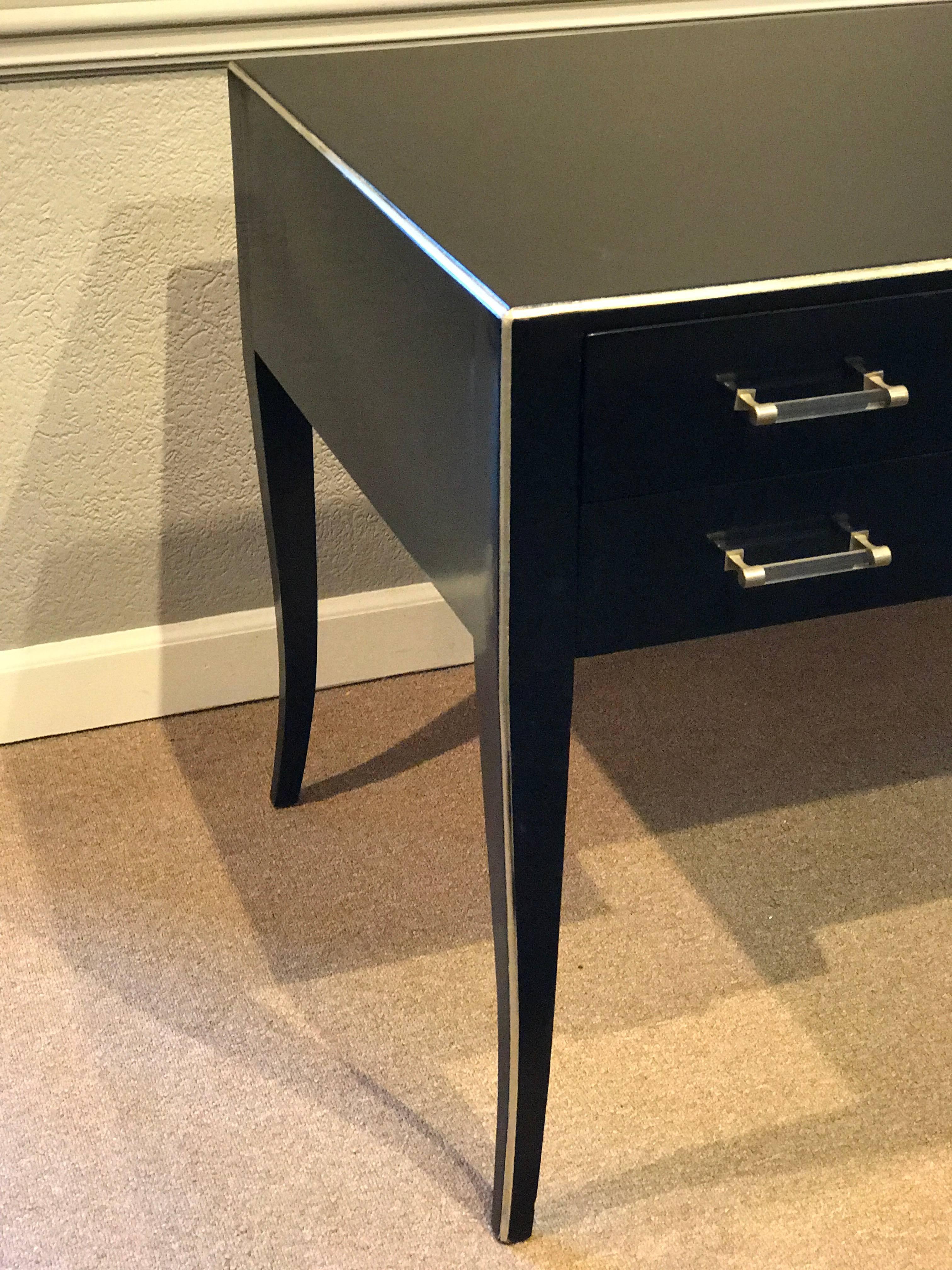 French modern design black lacquered desk with Lucite handles. Minimal and sleek with silver leaf trim, fitted with five drawers, raised on four tapering legs.
The desk opening is 25.5