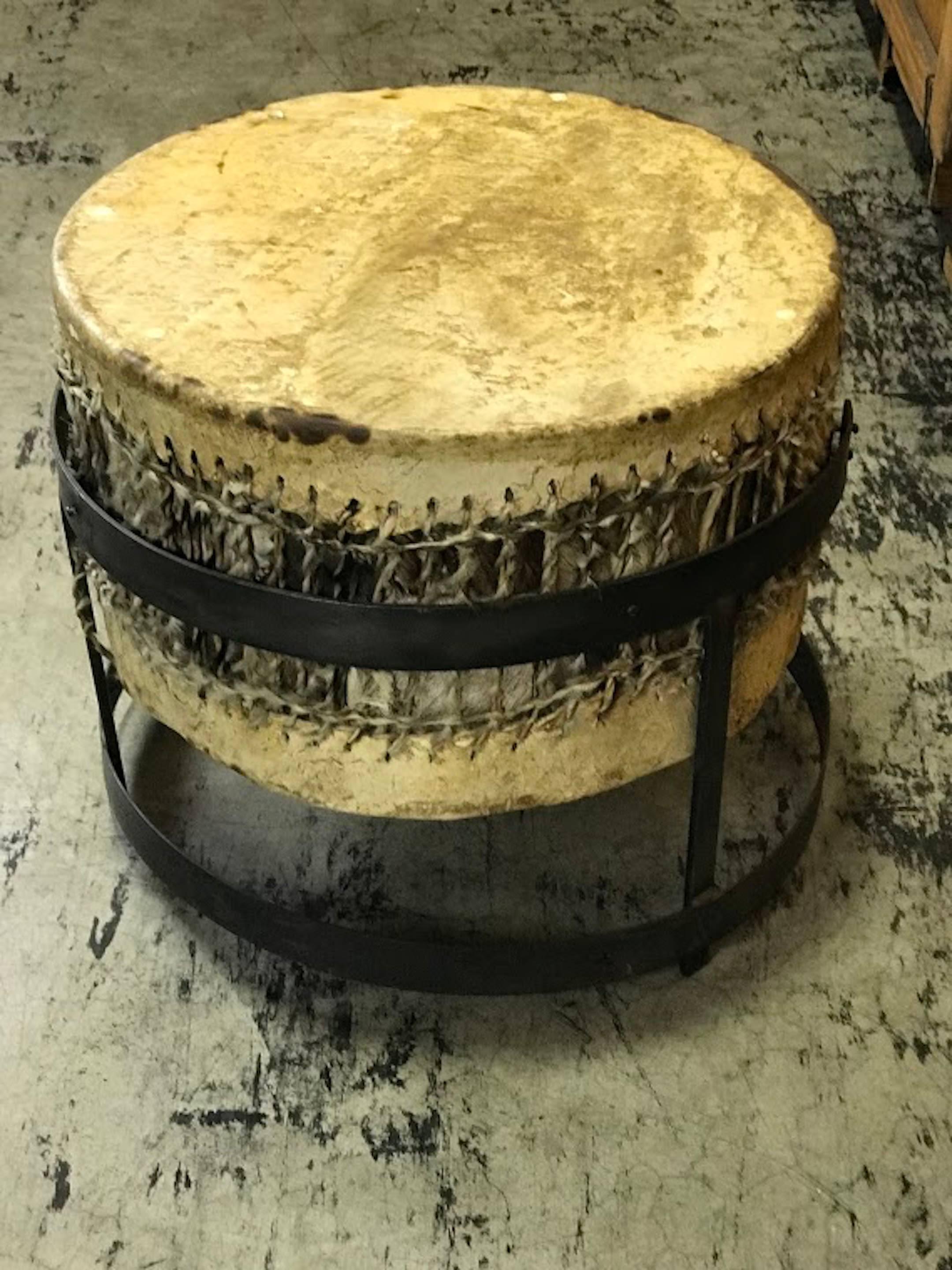 African drum table with forged iron pedestal base, of circular form with natural hide covering, very sturdy with even surface

    