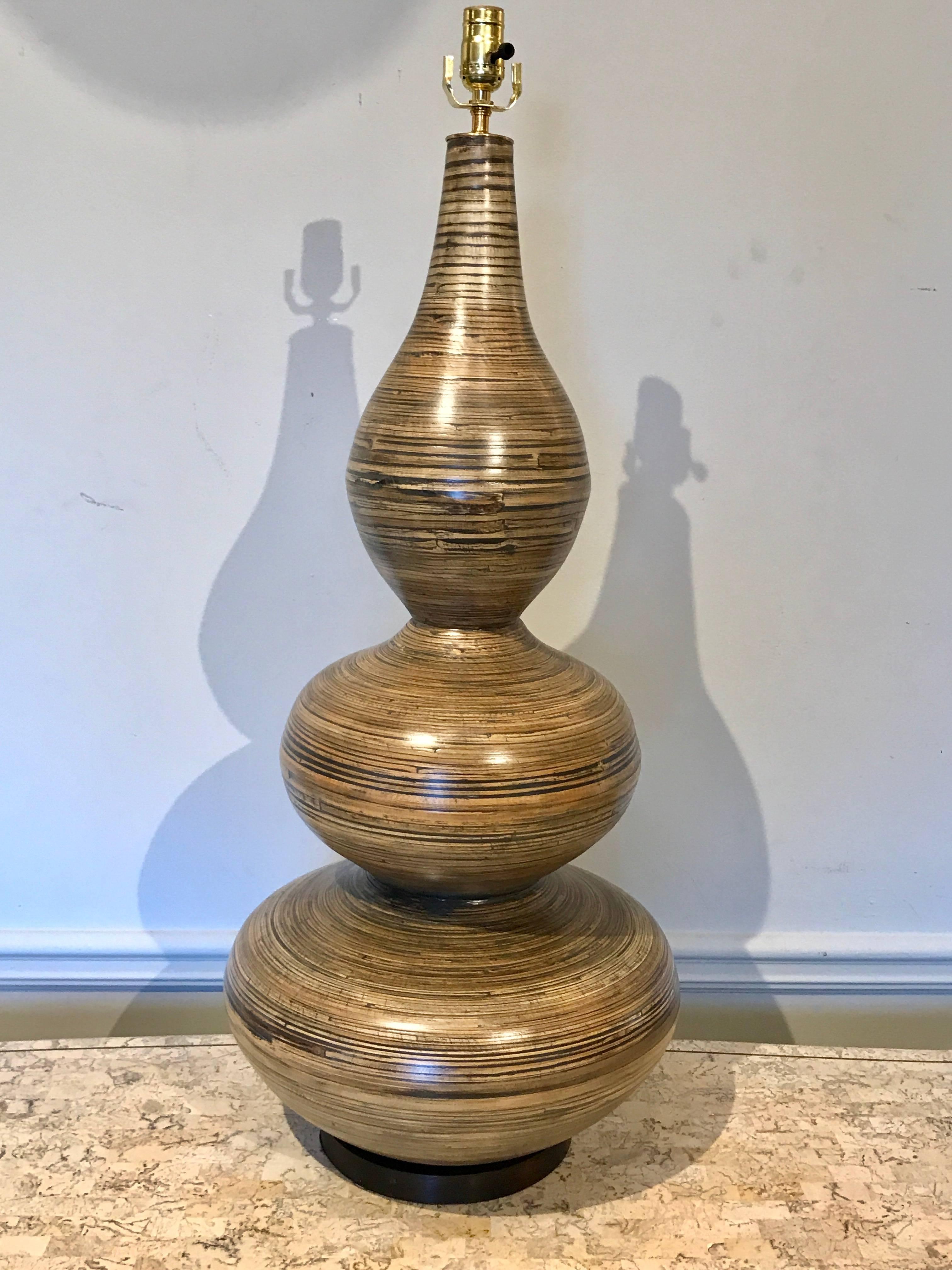 A stunning pair of large lacquered bamboo gourd lamps, each one standing 42" high to top of the socket 39" to the top of the vase, raised on custom circular ebonized wood plinth bases.
