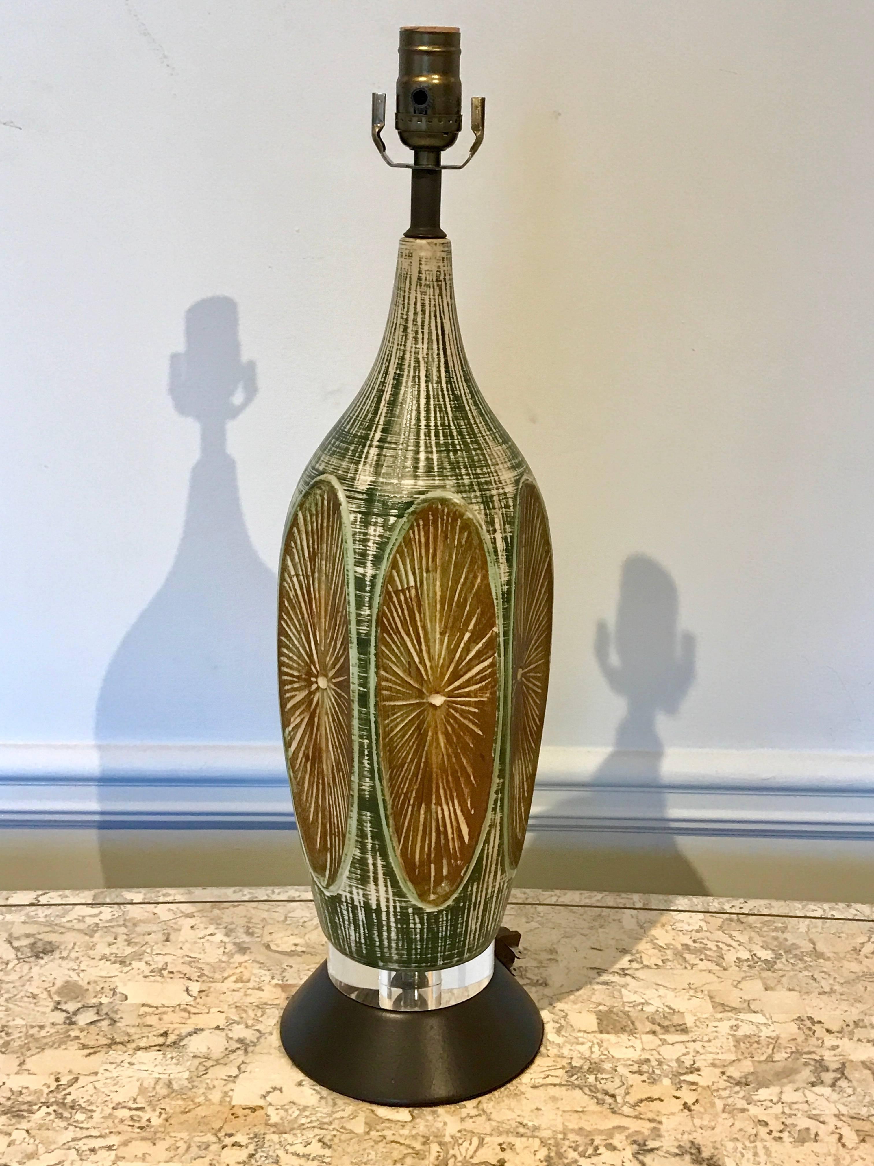 Pair of midcentury Lucite and Pottery lamps, each one with of brown and green oval incised decorated panels, raised on Lucite bases, newly wired
Measures: 19