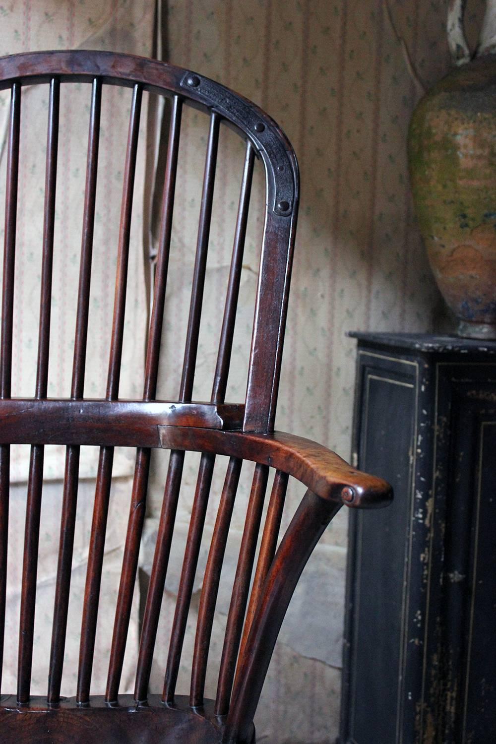 The beautifully crafted George III period hoop-back windsor armchair, constructed entirely in walnut, having a ten-stick high comb hoop back with two cast riveted iron brace struts to the rail. the scroll detailing to the shaped arms to a shaped