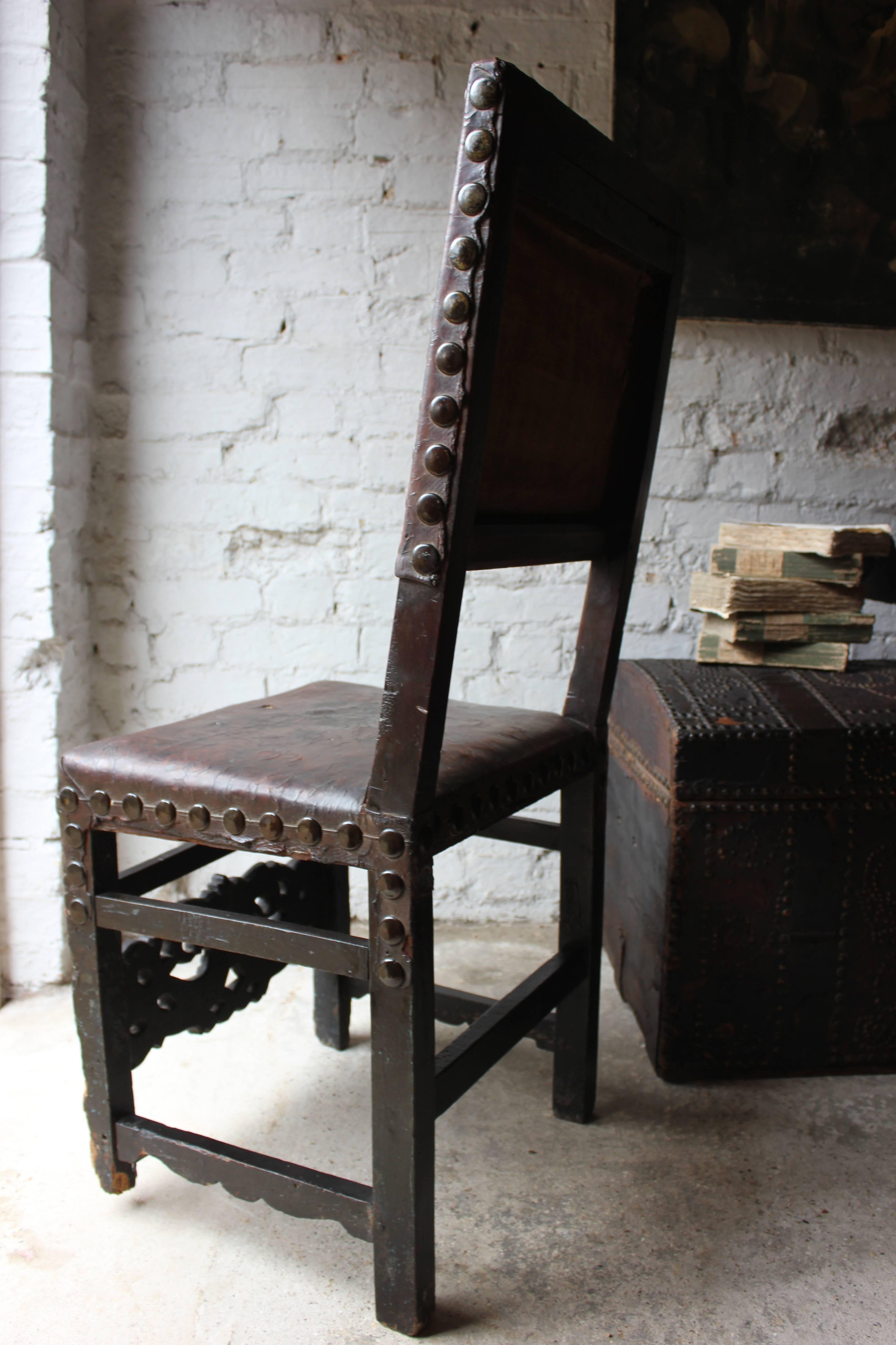 The 17th century hide-upholstered joined walnut side chair, with traces of an attractive blue paint remaining to the lower carving, the whole having a rectangular back and seat upholstered in hide attached with oversized nails, foliate carved and