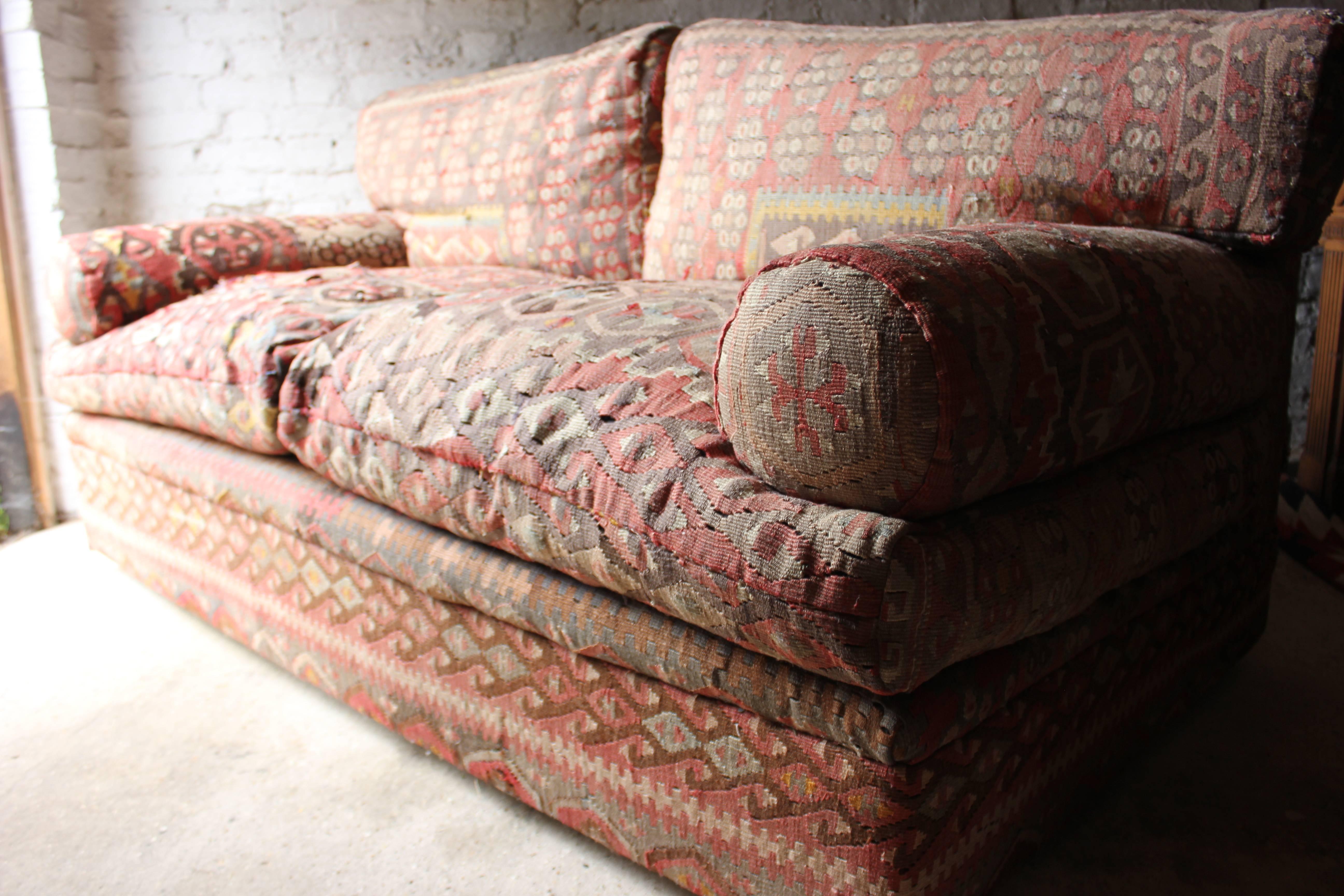 The large and comfortable three-seat sofa with Kilim upholstered to the whole, the quality frame, with rolled drop in arms, sitting on concealed castors, surviving from the fourth quarter of 20th century England and from the Fulham Road, George