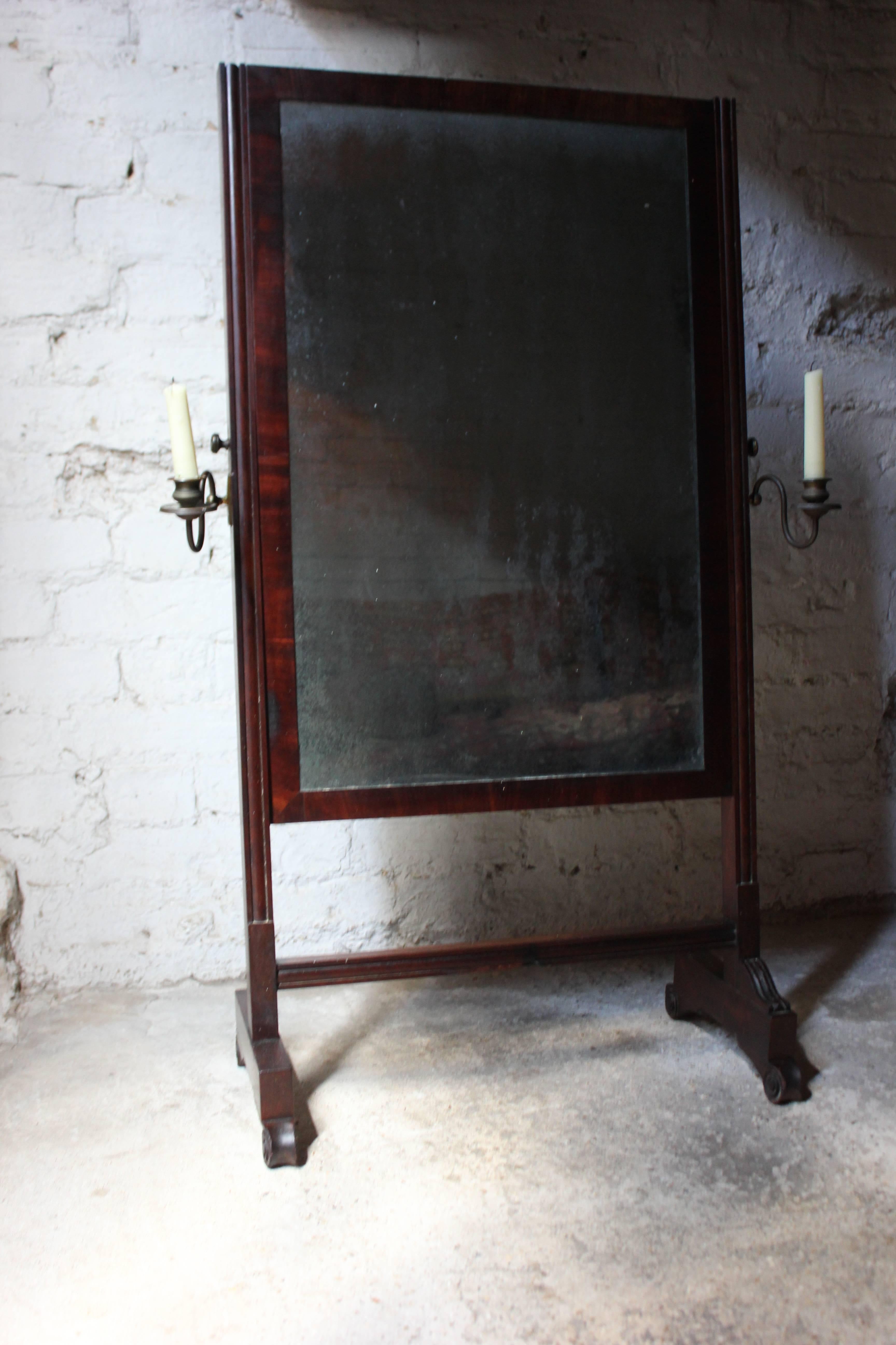 The very scarce child’s cheval mirror of the appropriate small proportions in beautifully original condition, showing the original clouded and foxed mirror plate, flanked by the original adjustable candle sconces, provincially crafted in pine with