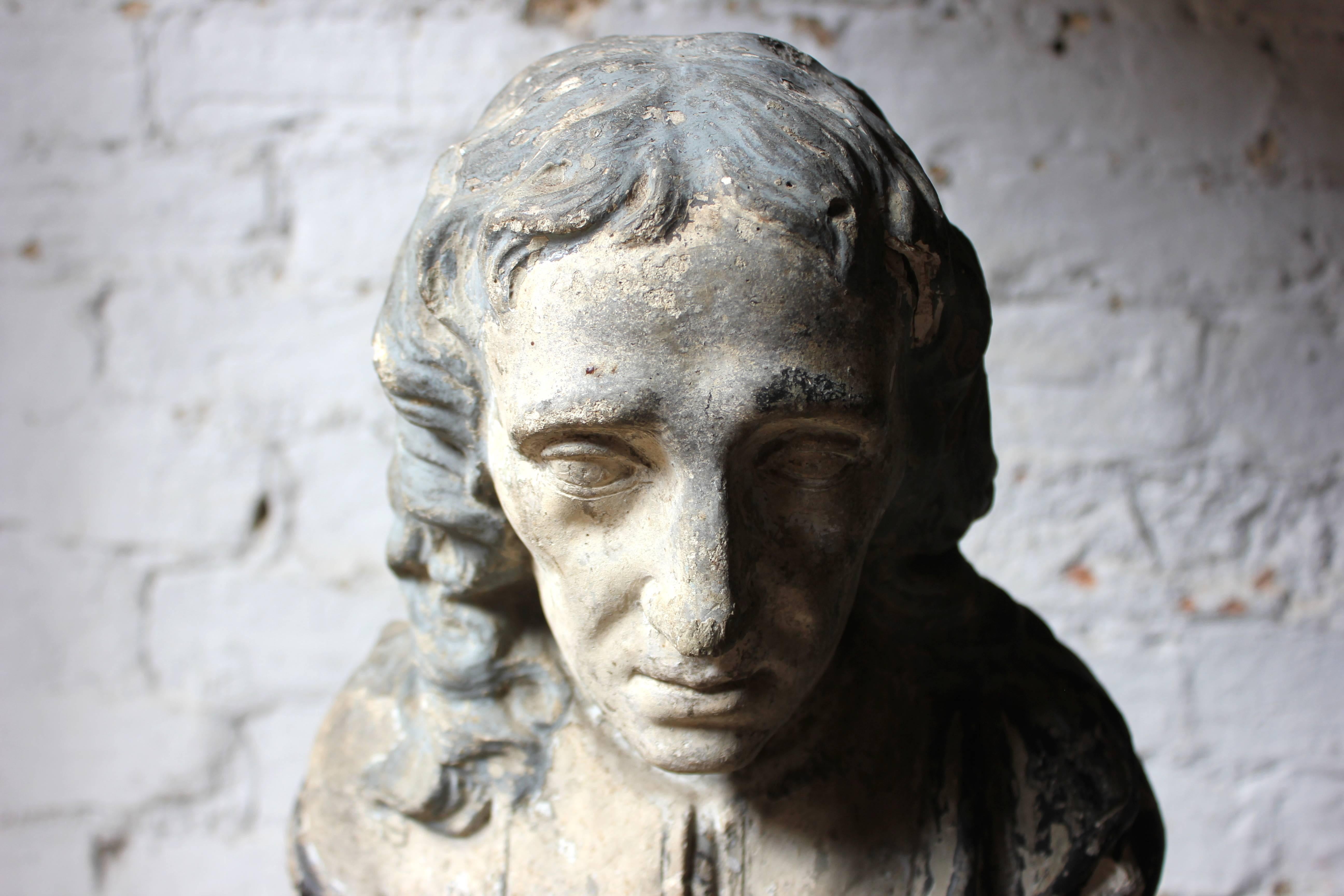 The late Victorian painted plaster library bust of John Milton (1608-74) wearing ceremonial robes and with a central cartouche reading ‘Milton’ on a weighted waisted socle base, survives from the late Victorian period in beautifully decorative