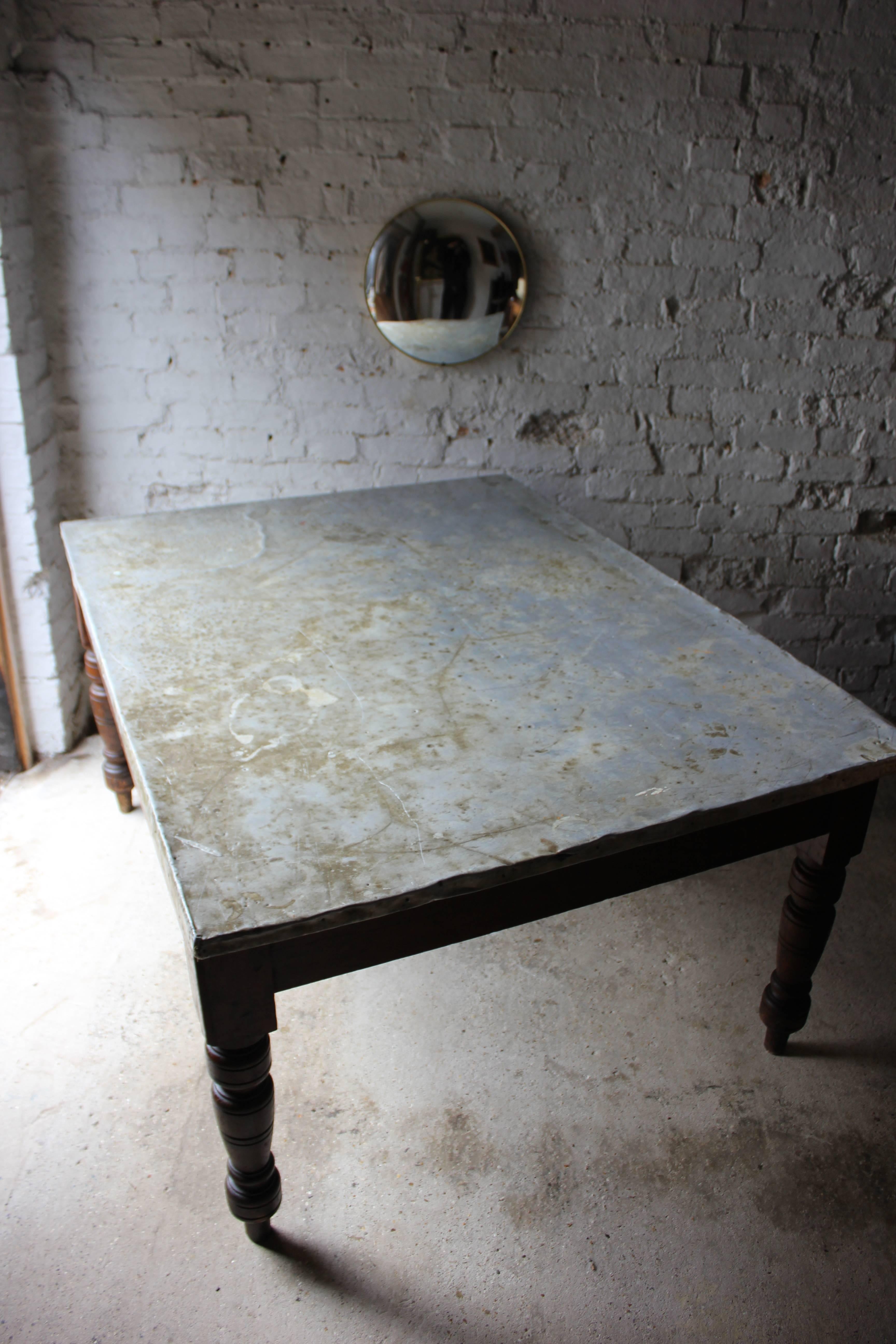 Of great character, the unusual Victorian stained pine kitchen or farmhouse table, later used as a preparation or work table, of good size and colour, having a rectangular top, later being covered by tacked on zinc, the whole on turned legs and