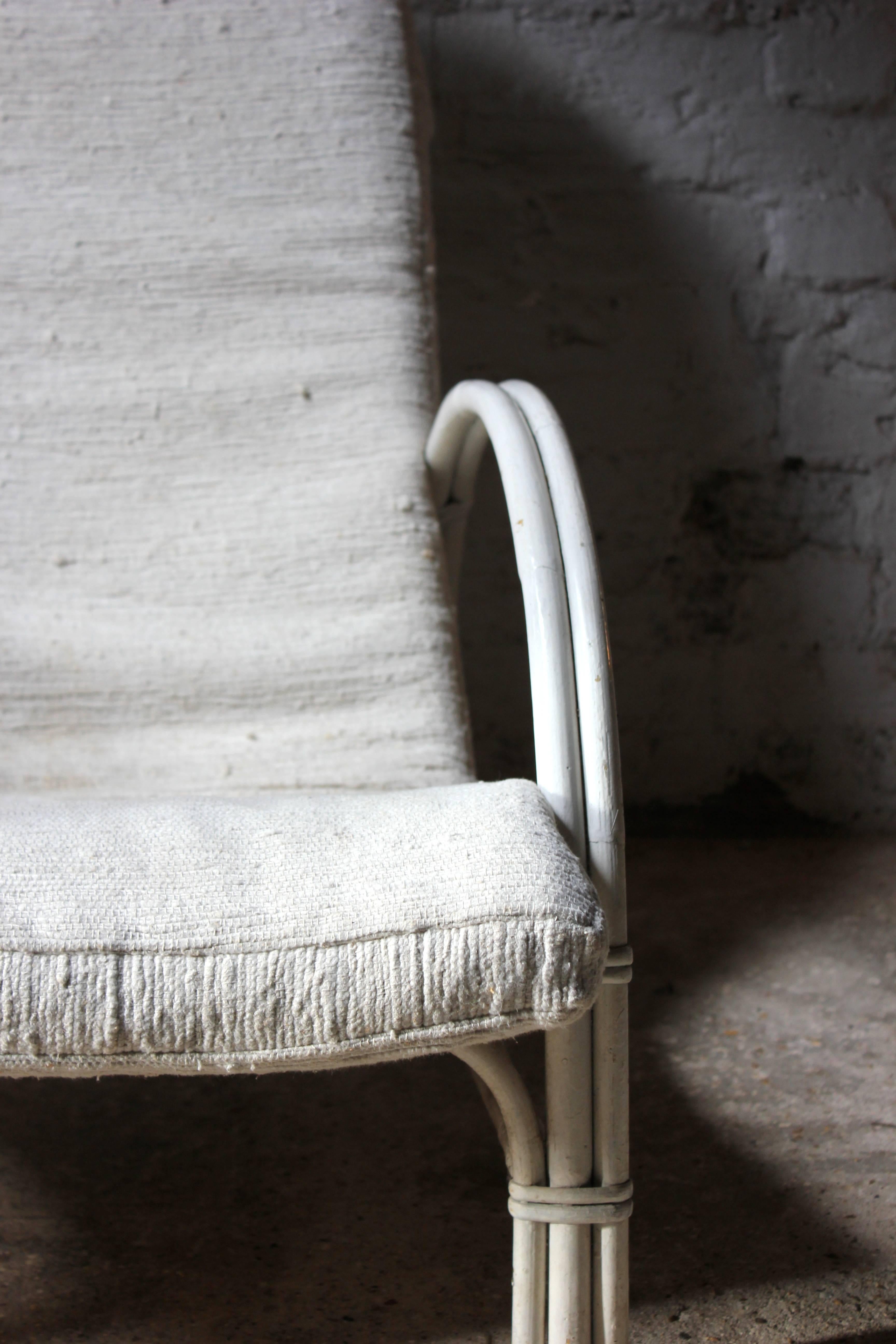 The beautifully sculptural wicker and bamboo white painted low frame, having elegantly Art Deco inspired shaped half moon arm supports, with a cream berber Moroccan wool drop in shaped padded roll seat by Terence Conran, bearing an ivorine plaque
