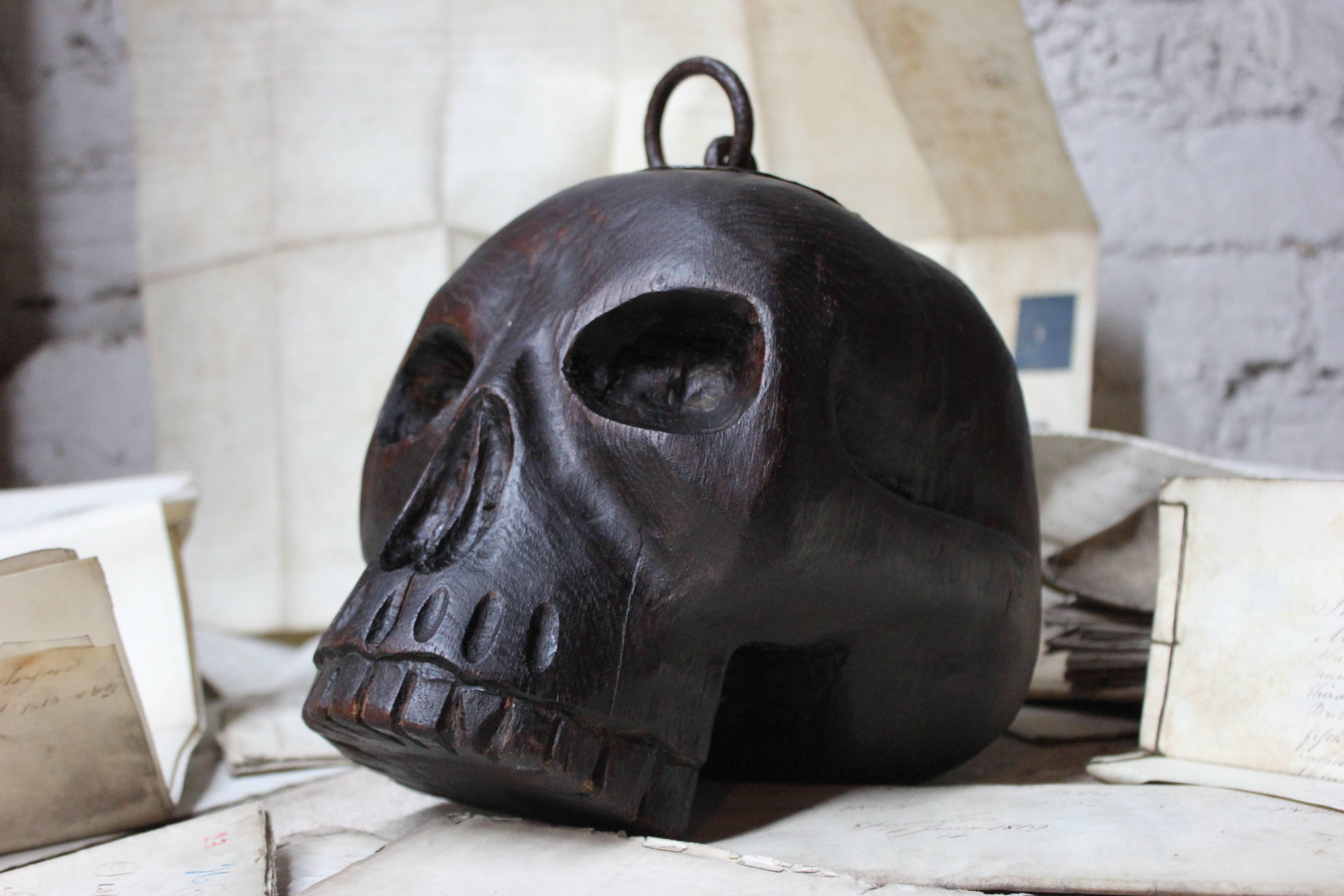 The unique oak Momentum Mori door stop, being carved in the round as a slightly larger than life-sized human skull mounted with an iron ring handle to the top and with a beautiful Primitive iron-strap repair, the whole with a superb patination and