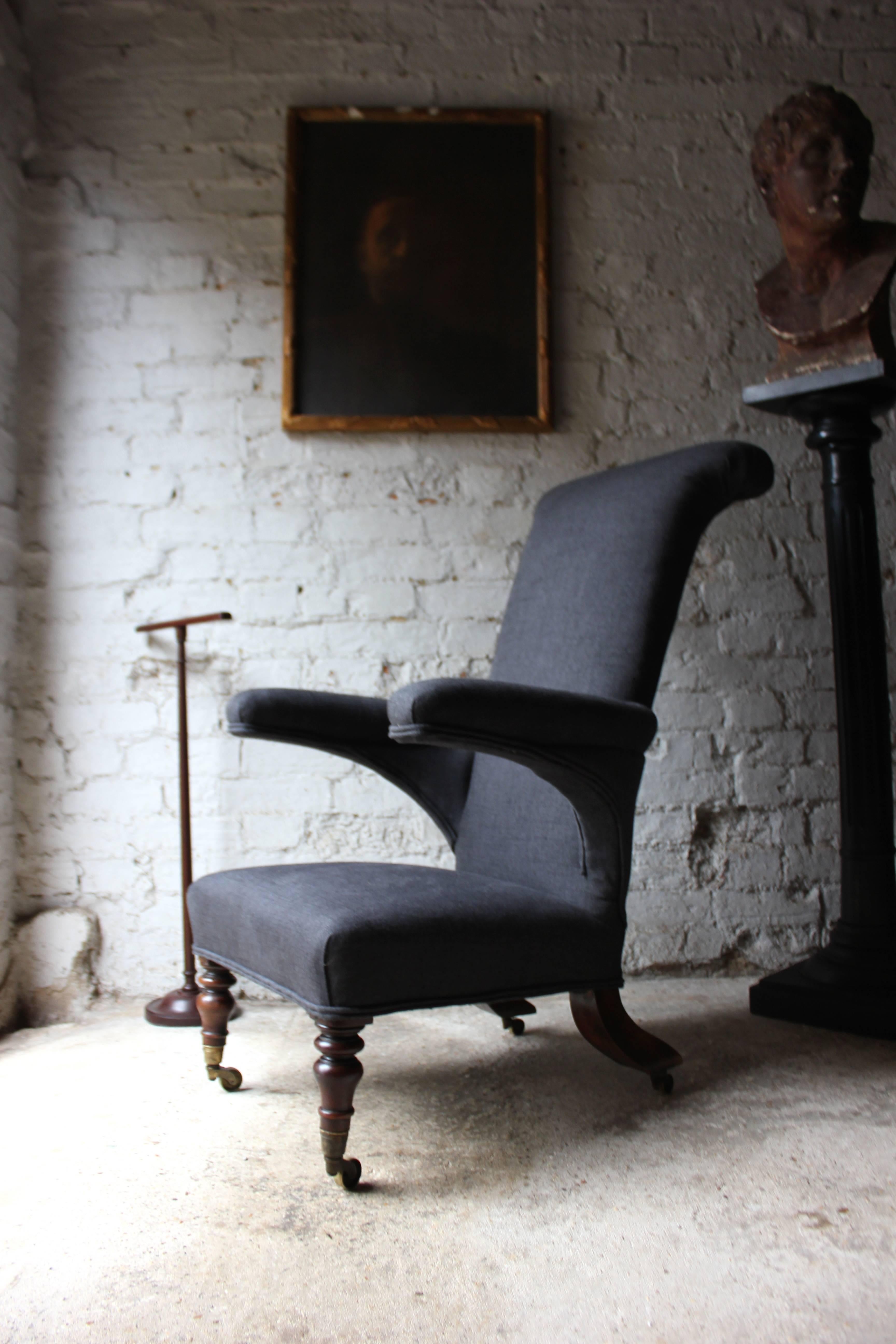 The good quality whole of unusual and sculptural form, of prie-dieu type, being upholstered in a charcoal tuscan linen with double piping, featuring an pair of under-swept arms to a high angular back with curved crestings, the padded seat to well