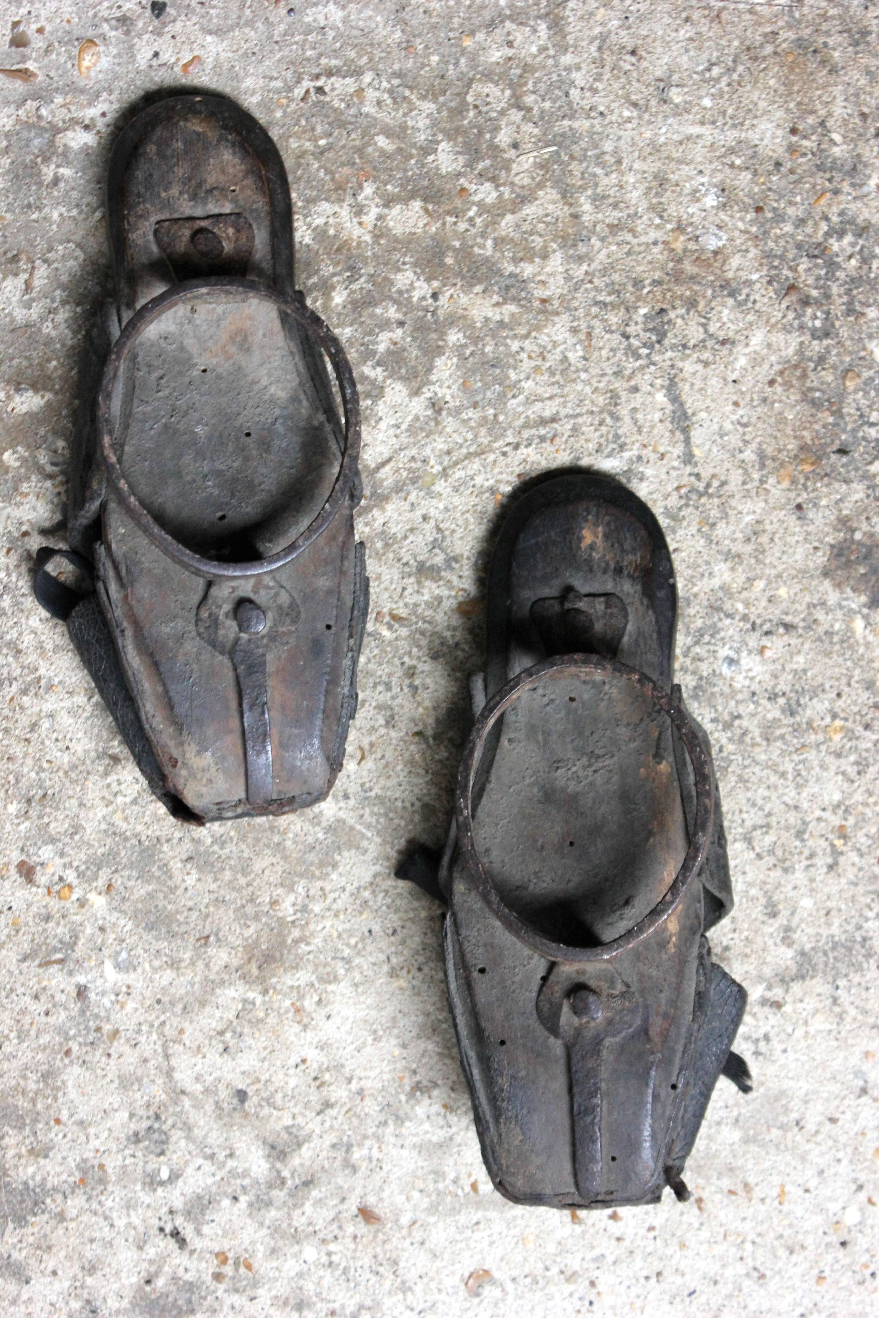 The rare pair of late 17th-early 18th century child’s pattens or overshoes, each having a leather quarter, vamp and toe cap embossed with shells and scrolls to carved wooden soles shod with wrought iron rings and strap-work, the pair surviving from