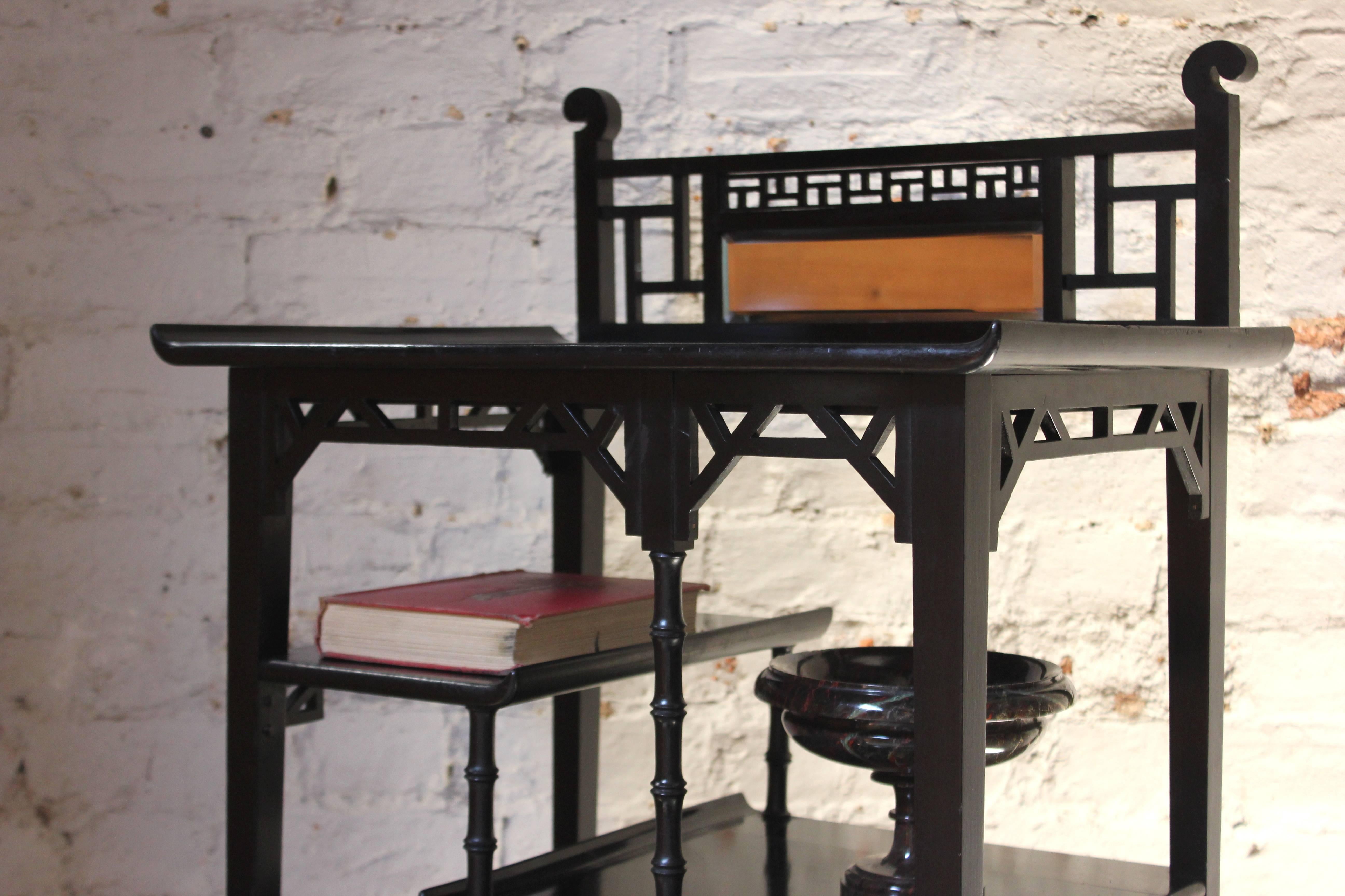 The good quality ebonised étagère, in the Anglo-Japanese manner, having pierced decorative rails, faux bamboo turned supports and counterbalanced shelves with pagoda upturns, to a lower galleried shelf, with the original beveled mirror to the