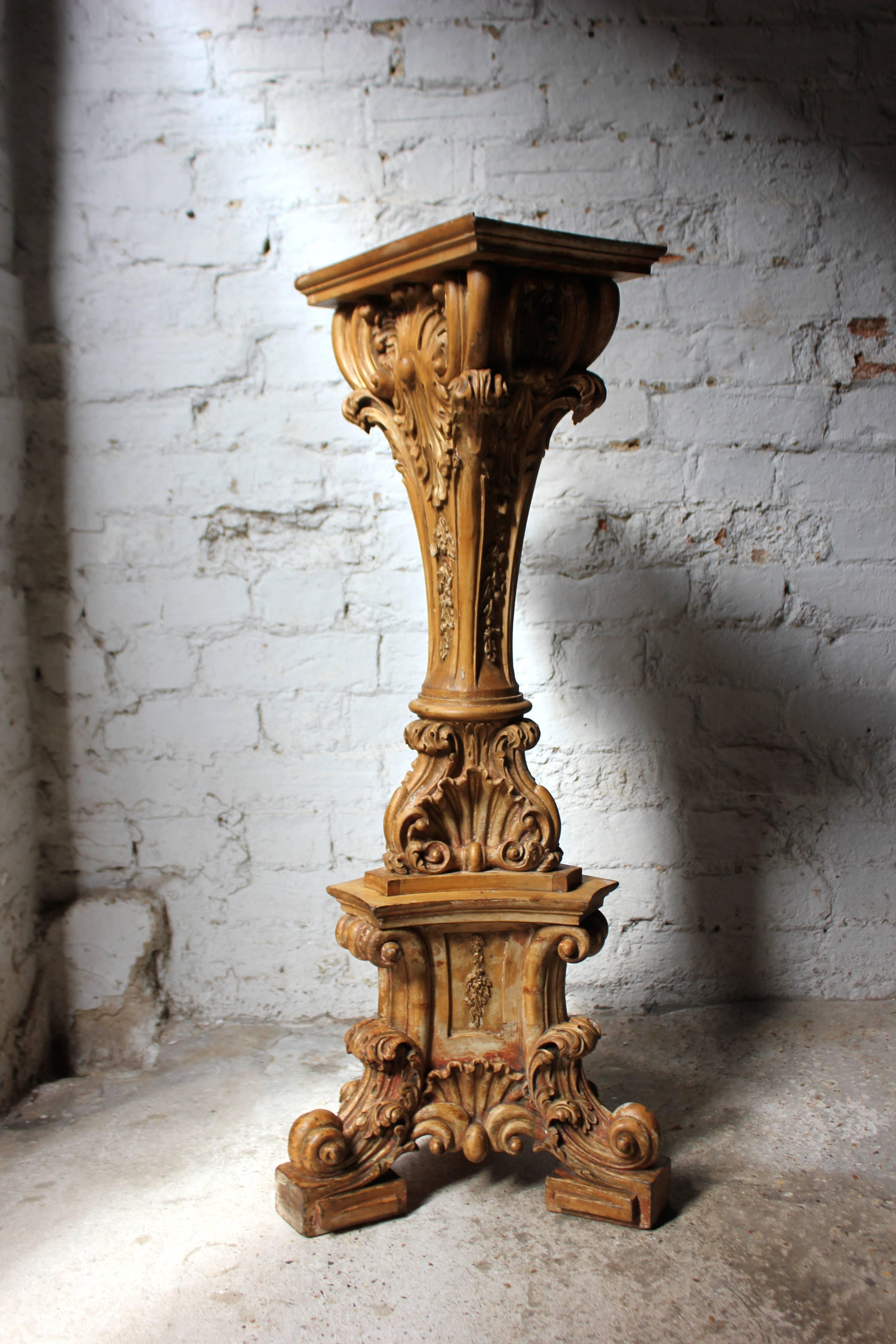 The well-proportioned limewood torchère with traces of the original gilding to the carved decoration, having a rectangular shelf top over a waisted triform column profusely carved with C-scrolls, acanthus and oak leaf trails, on a tripartite base