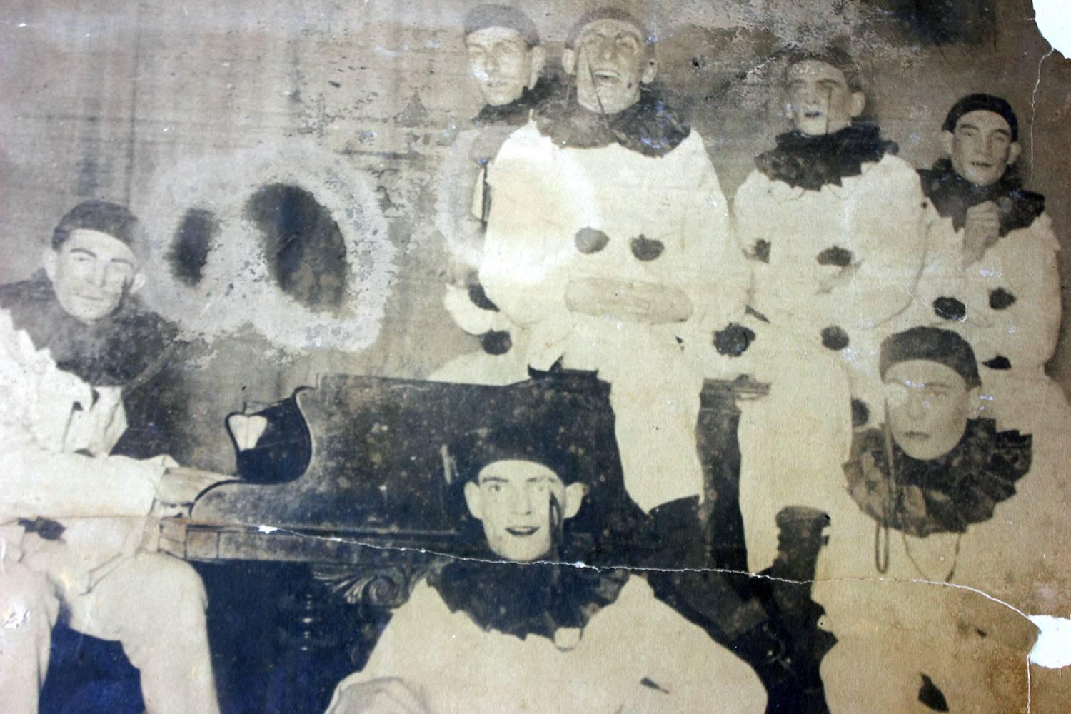 The unusually large and scarce framed and glazed studio photograph showing a troup of seven male pierrot clowns, dressed in the traditional black and white assemblage, one member sitting on a Thonet bentwood chair and playing on a piano, each with