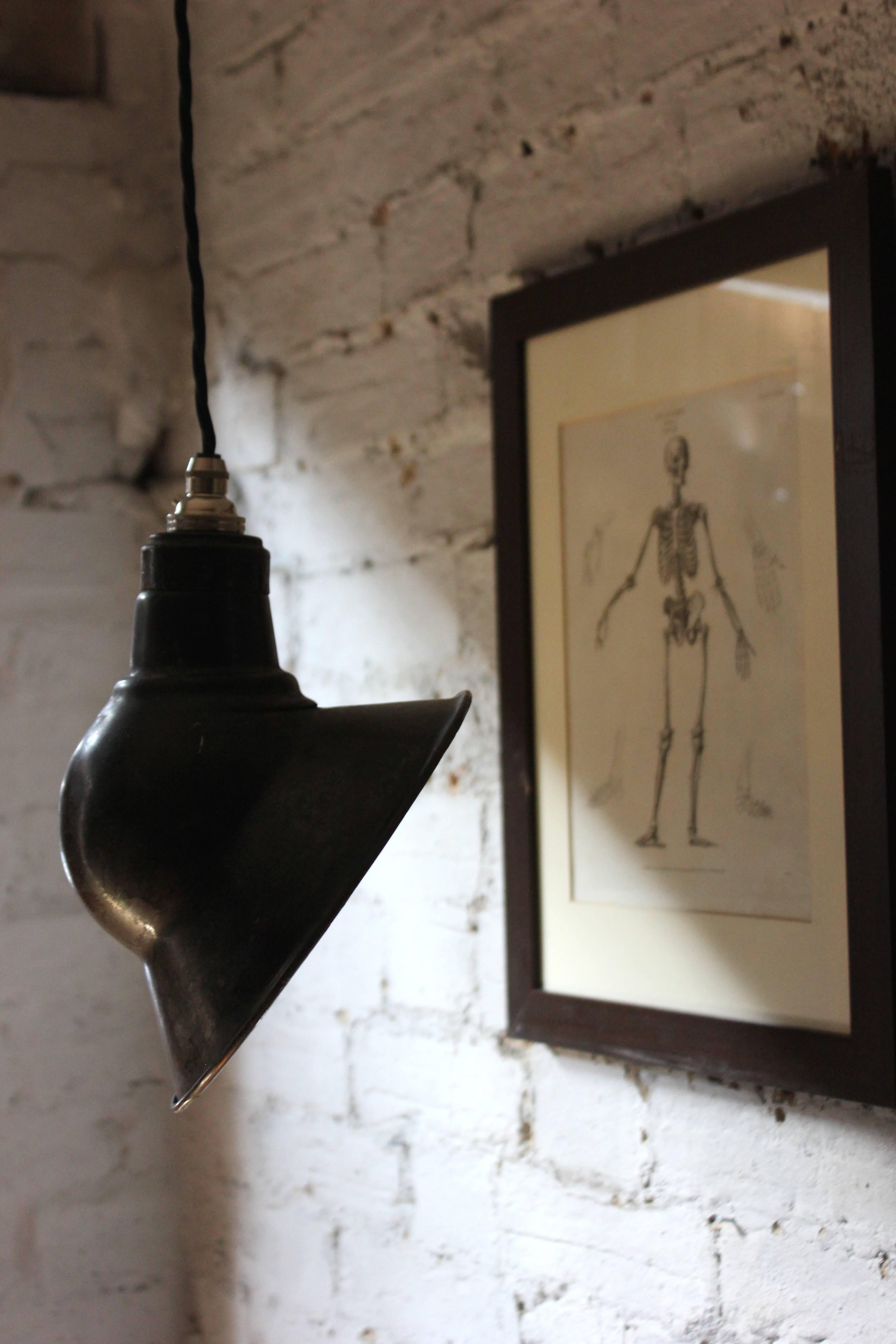The stylish black enamel pendant hanging light bearing a good patination to its surface, and of rather unusual shape, surviving from Mid-Century England.

The light fitting is in very good and original condition. The whole does not suffer from