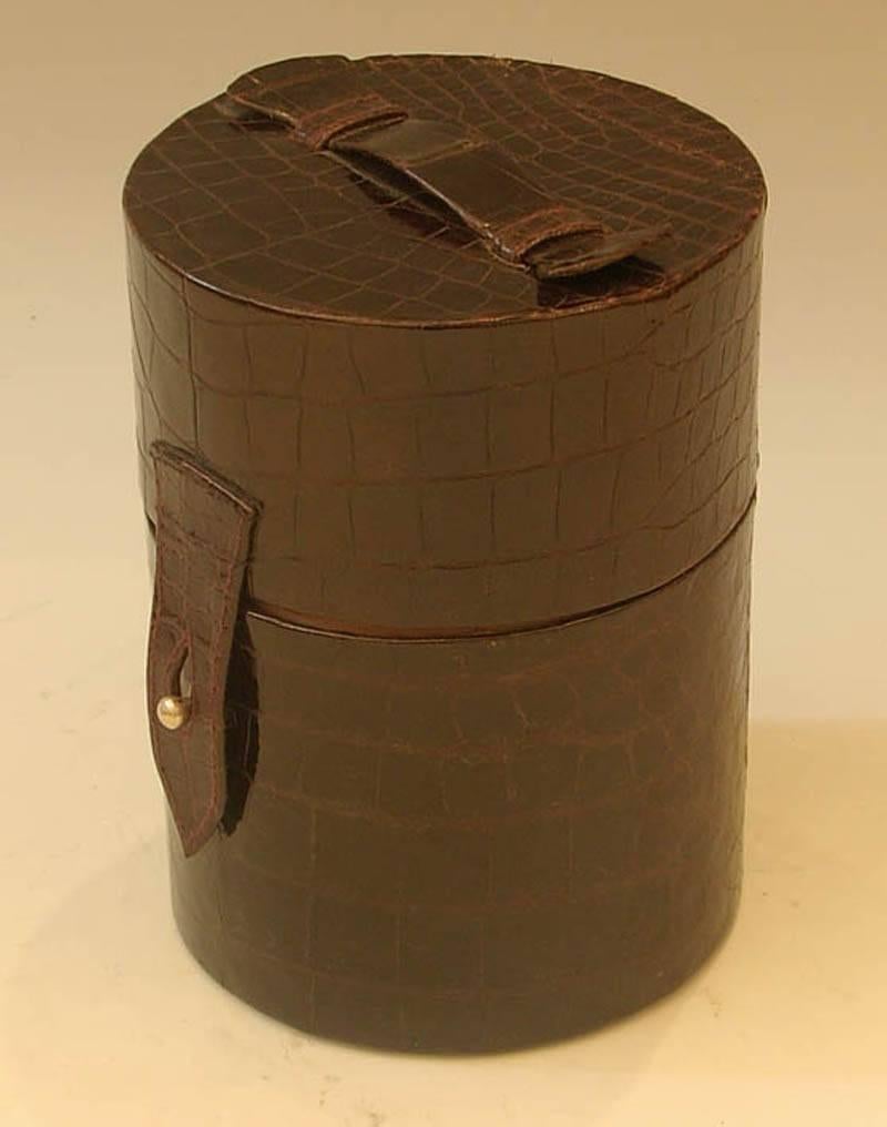 A Crocodile skin cased travelling cocktail set, circa 1920.

Made by James Dixon and Sons. Containing one x shaker, six cups, three curved flasks and one bittes jar.

In stunning almost unused condition.

Approx. 10 inches high.