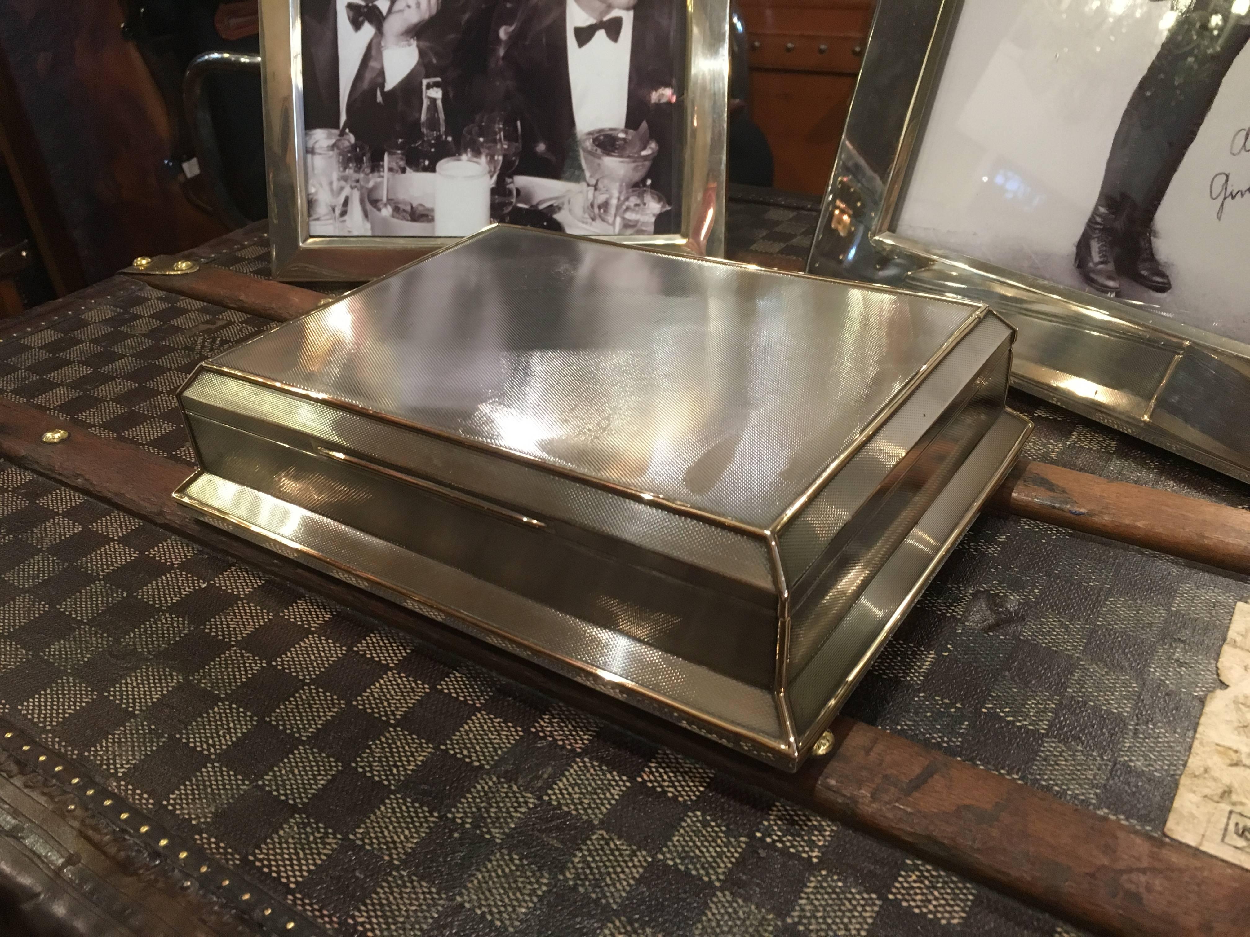 A gorgeous Art Deco styled sterling silver and gold cigar / cigarette box by Asprey of London. The box has lovely engine turned decoration throughout and heavily styled canted edges.

A very generous size, measuring 9 1/2 inches wide, 7 1/2 inches
