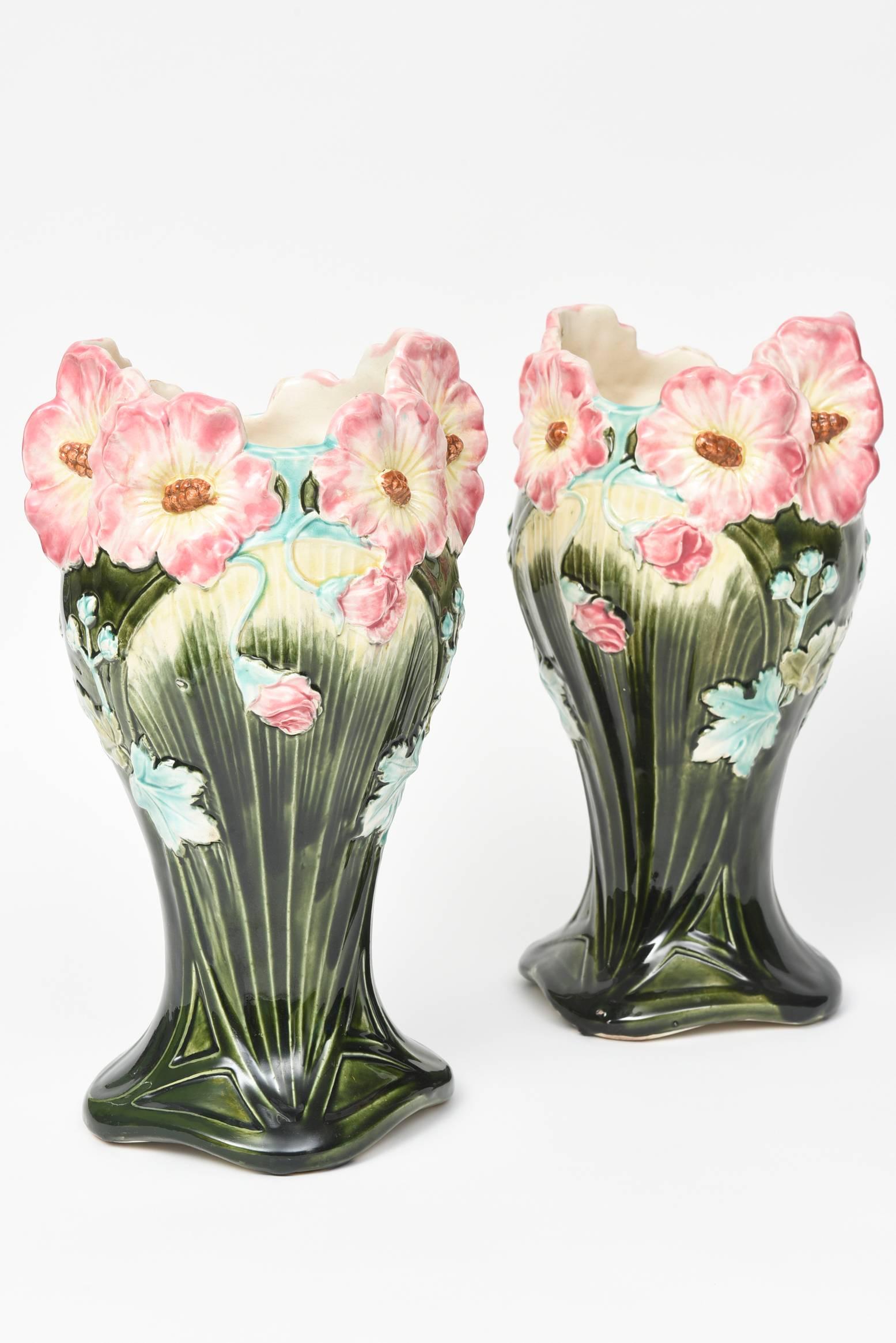 This pair of French Majolica floral vases were produced during the Art Nouveau period. The base is a dark green with pink flowers at the top edge with lighter green leaves. These are so stunning they do not even need flowers inside them. Measures: