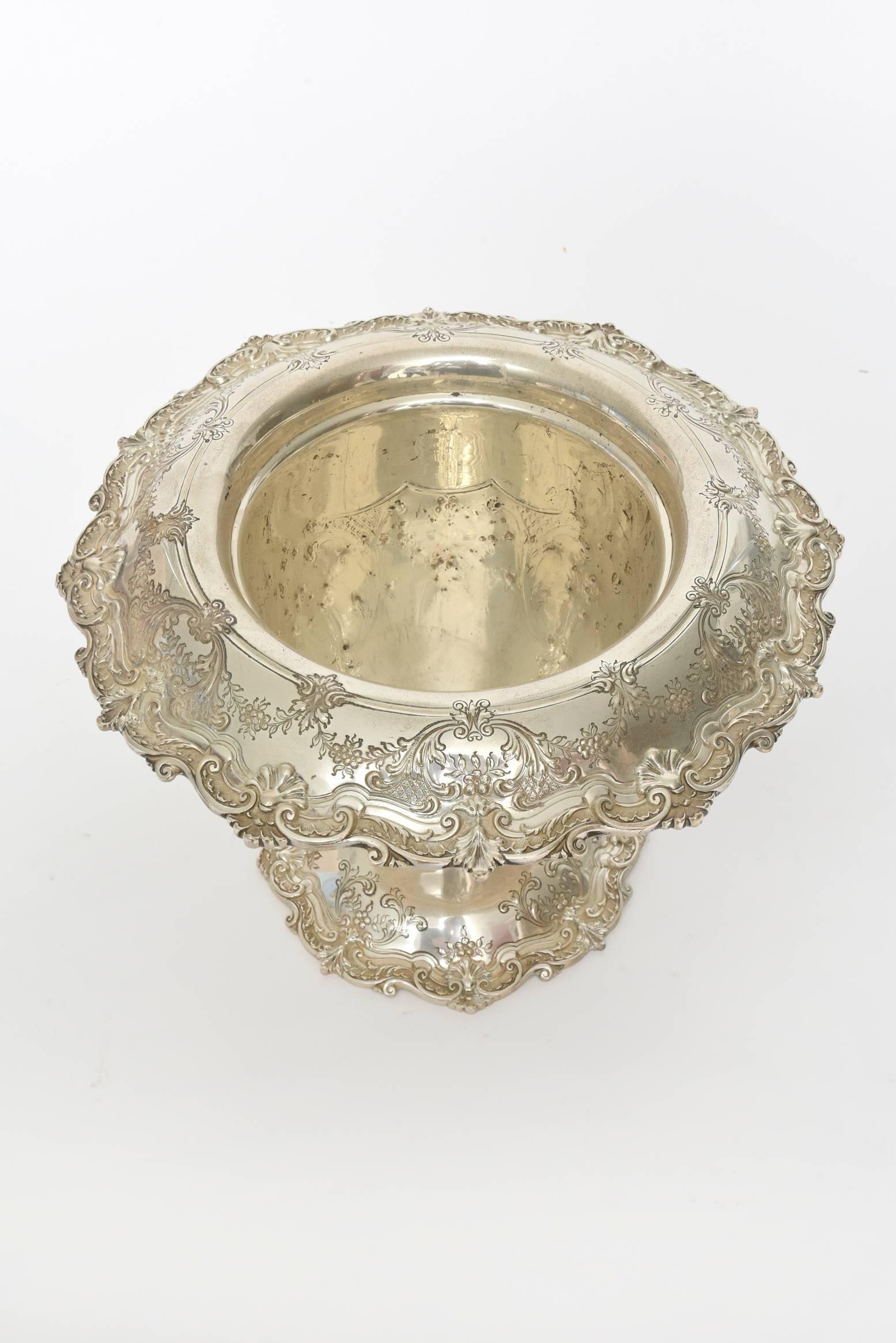 Ornate Graff, Washbourne & Dunn sterling silver champagne bucket (also could be used as a vase or centerpiece) features scalloped foot and rim. The piece is decorated with leaf and flower scroll wreaths and garlands as well as flowers against a