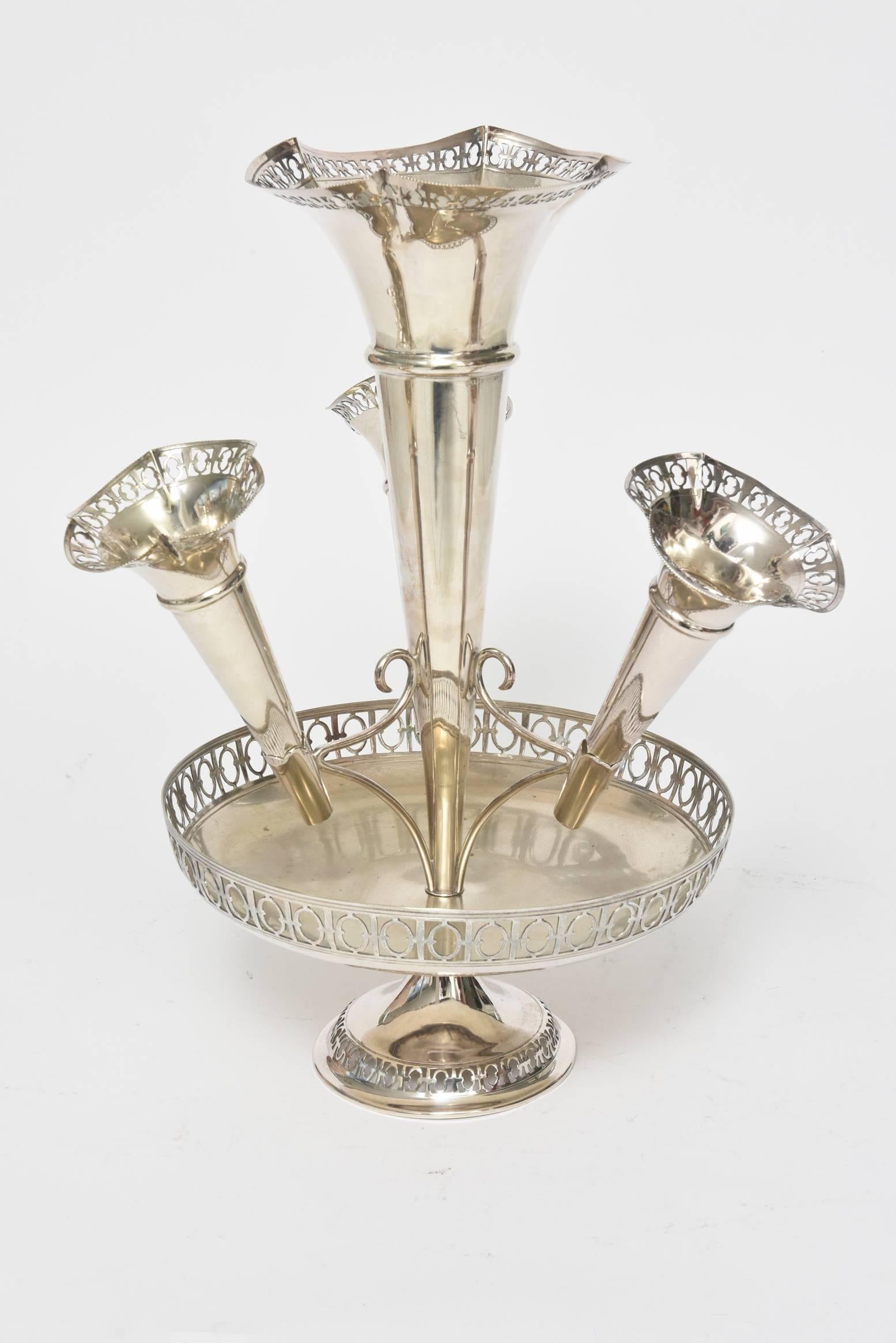 Diese schöne Epergne wurde von S.J. hergestellt. Levi & Co. (1901-1938) in Birmingham, England, zu Beginn des 20. Jahrhunderts.  Dieses beeindruckende Stück aus Silberblech besteht aus einer großen Trompetenvase in der Mitte und 3 kleineren Vasen,