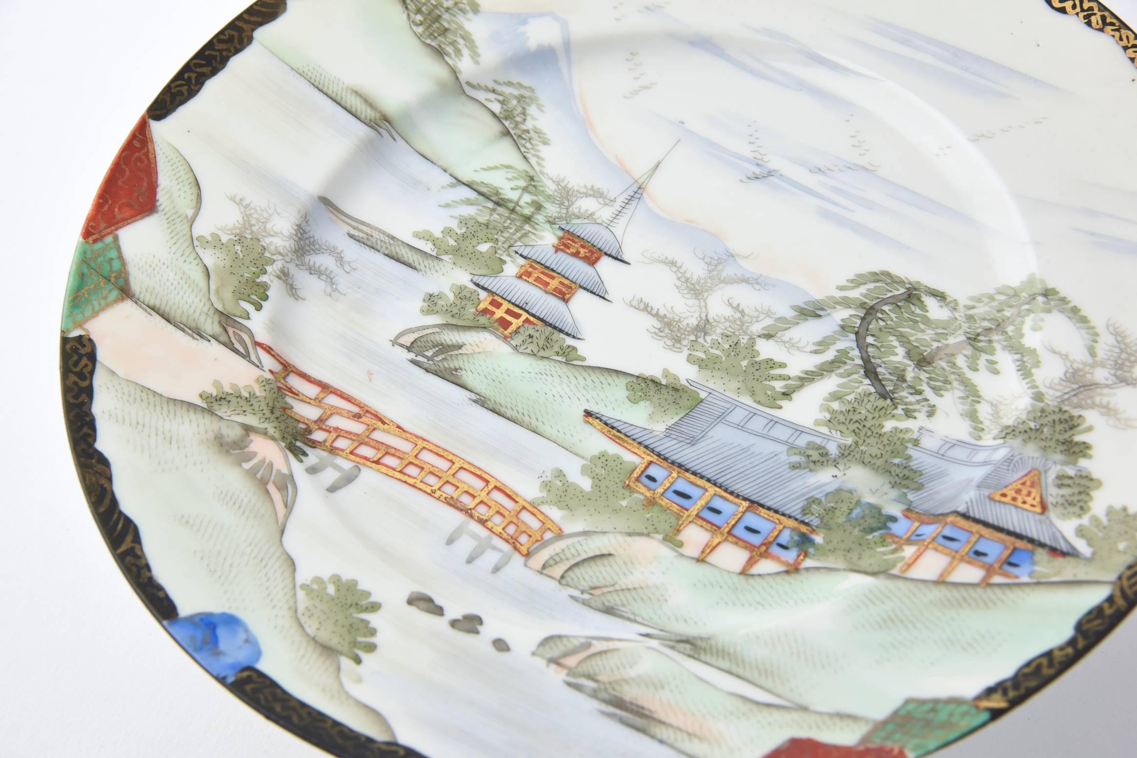 Pair of Japanese compotes hand-painted with Mount Fuji in the background of a classic Japanese village design. The village features a picturesque brook with a textured bridge accented by hidden pagodas in classic Japanese garden motif. The backs are