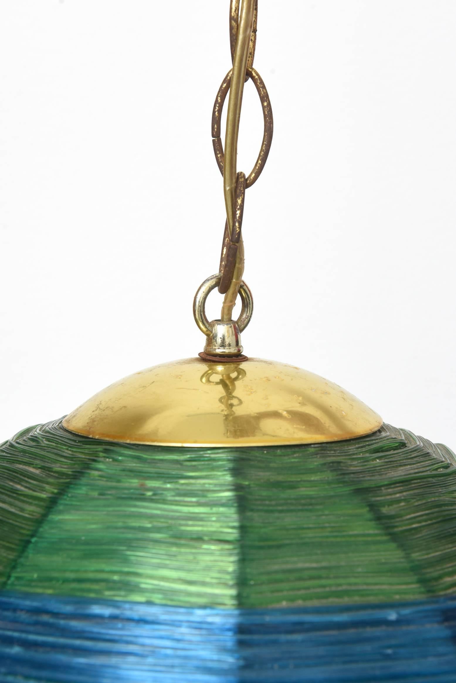 Midcentury woven fiberglass swag light.
Mid-Century Modern woven fiberglass swag light. This swag light has a lovely woven green and blue ball that is in very good condition. It plugs into the wall and has a cord going through the chain which is