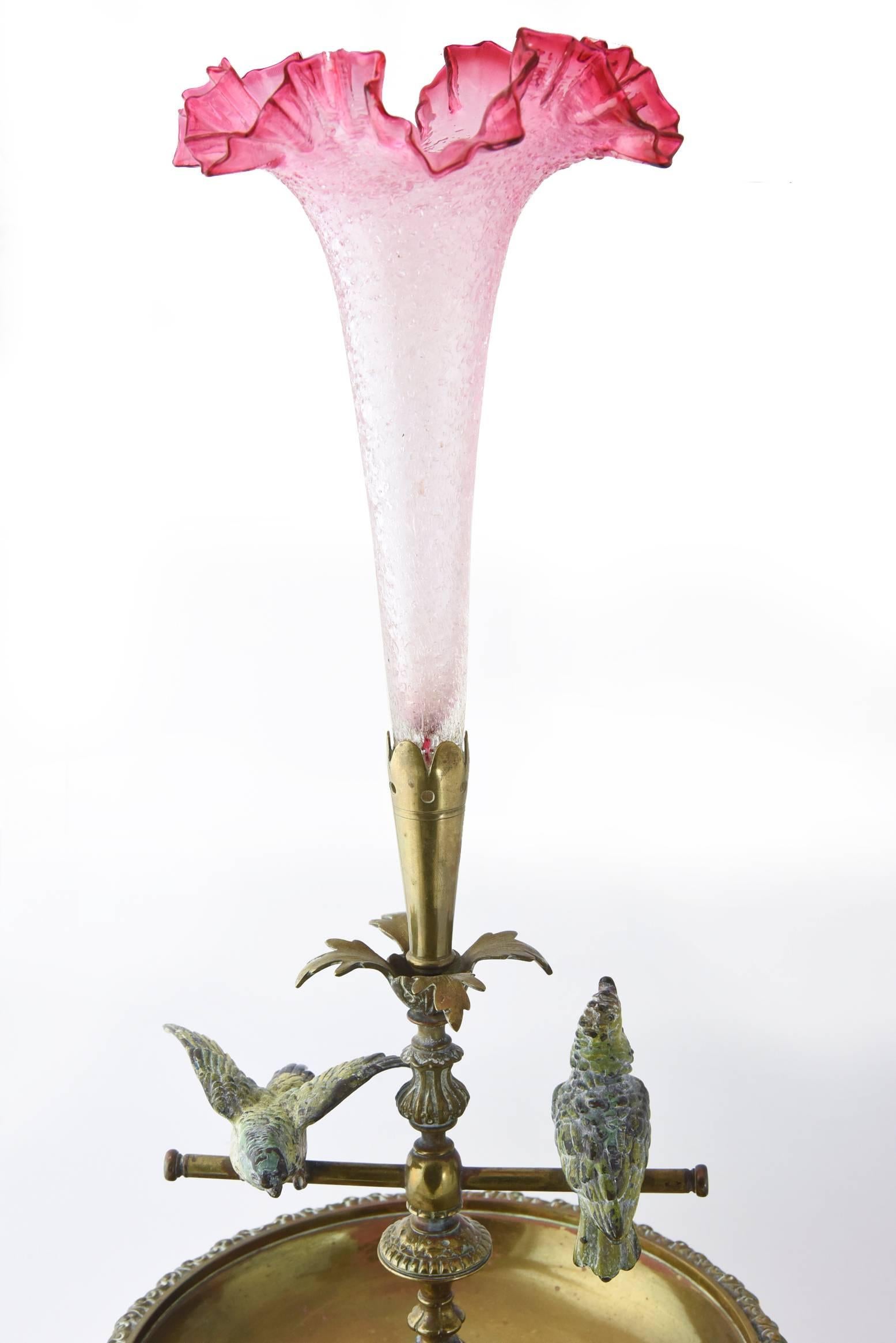 Early 20th century Epergne centerpiece with two Vienna bronze cold painted cockatiels on teeter totter swings with a beautiful crackled pink ruffled art glass tulip vase. The piece is unsigned.