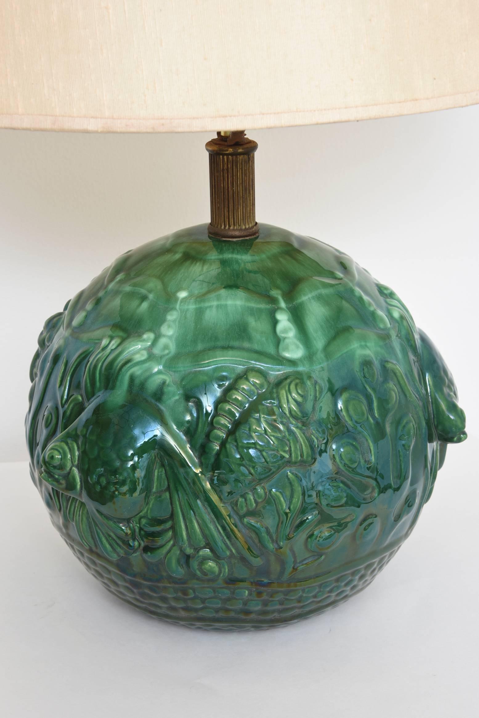 Stunning French Art Deco green ceramic lamp featuring fish playing in coral on a sandy bottom under the waves.

Shade not included. The height below is to the top of the shade. The ceramic section only is approximately 12