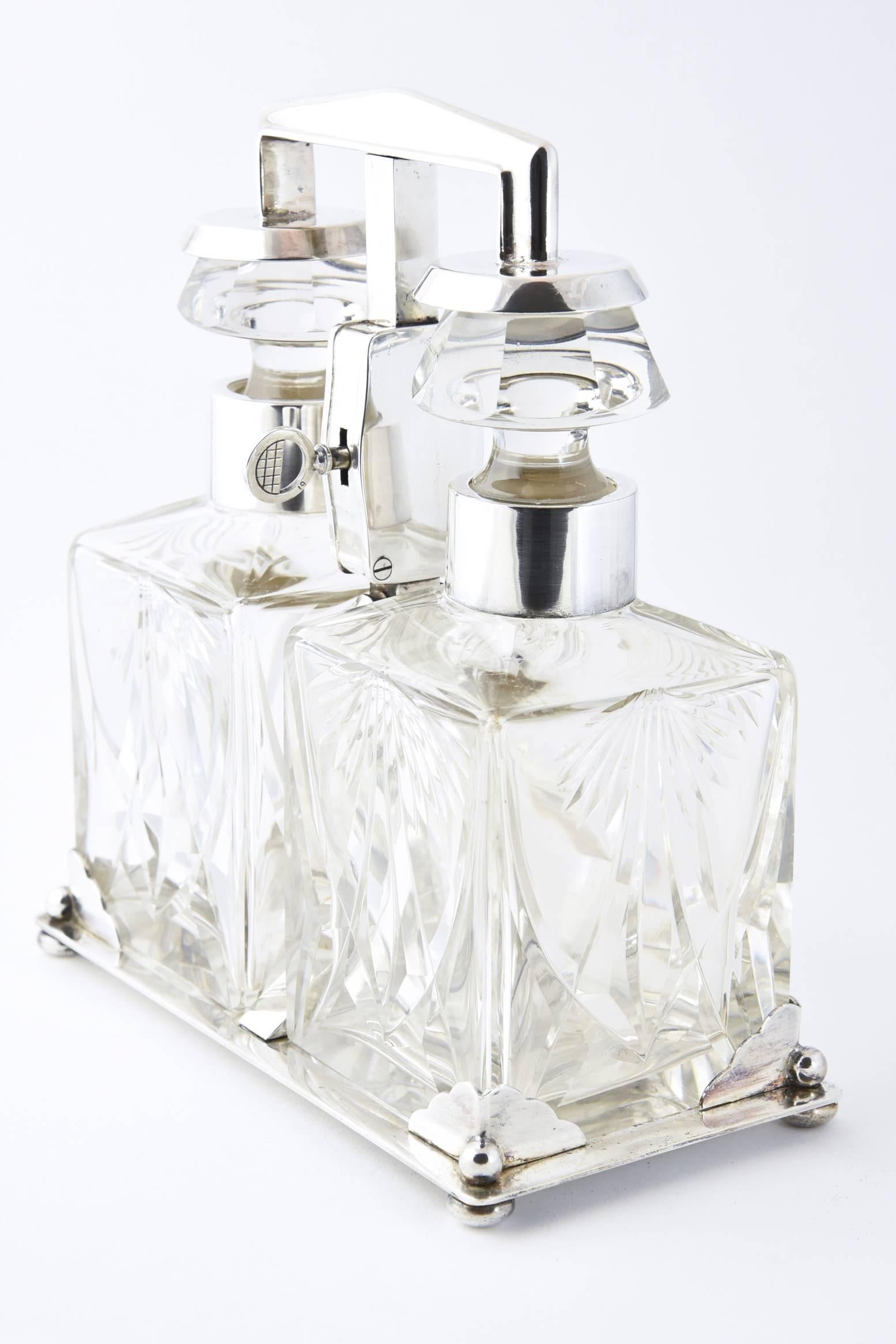An Art Deco tantalus in a WMF silver plated frame, circa 1920, two squat rectangular cut-glass decanters with silvered mounts and having faceted mushroom style stoppers, enclosed in a lockable frame, marked WMF.
    
