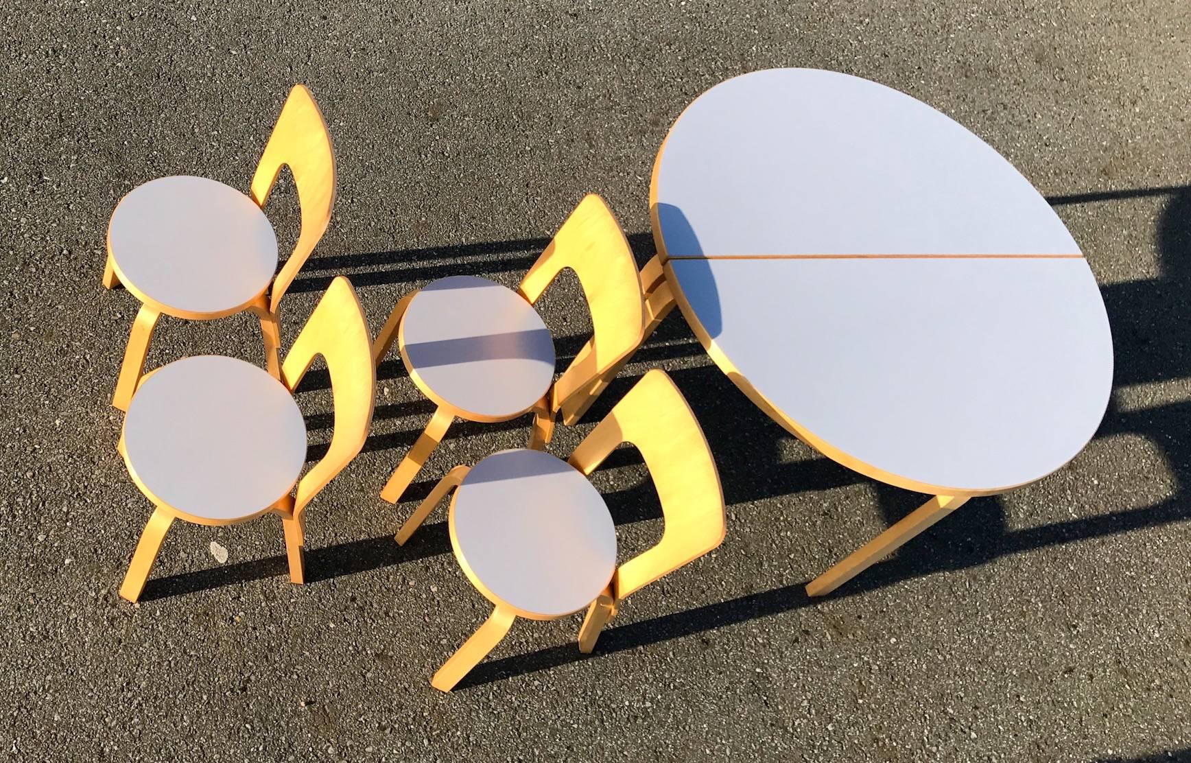 The set consists of four iconic chair 66 with grey laminated seat tops and two half circular tables number 95. Designed in 1935 by Alvar Aalto the set is still in production. The grey colored seats are not in production any more. All six pieces are