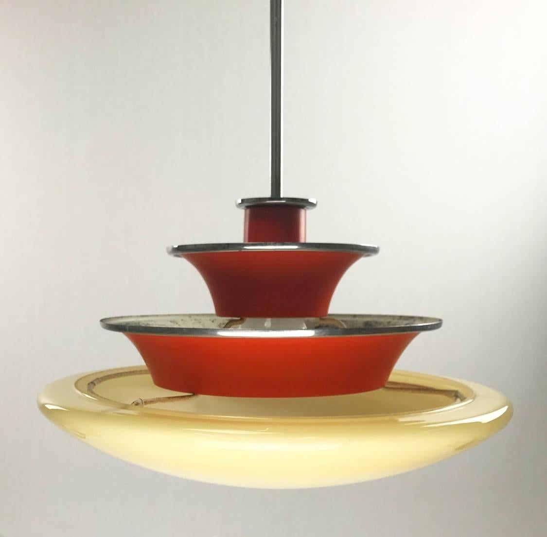 Extremely rare piece of Swedish Art Deco by Böhlmarks, mid-1930s.

The chandelier consists of a chrome canopy and rod, red/orange lacquered top shades and creme colored bottom opaline glass. 

Condition: Urestored because condition is stunning. No