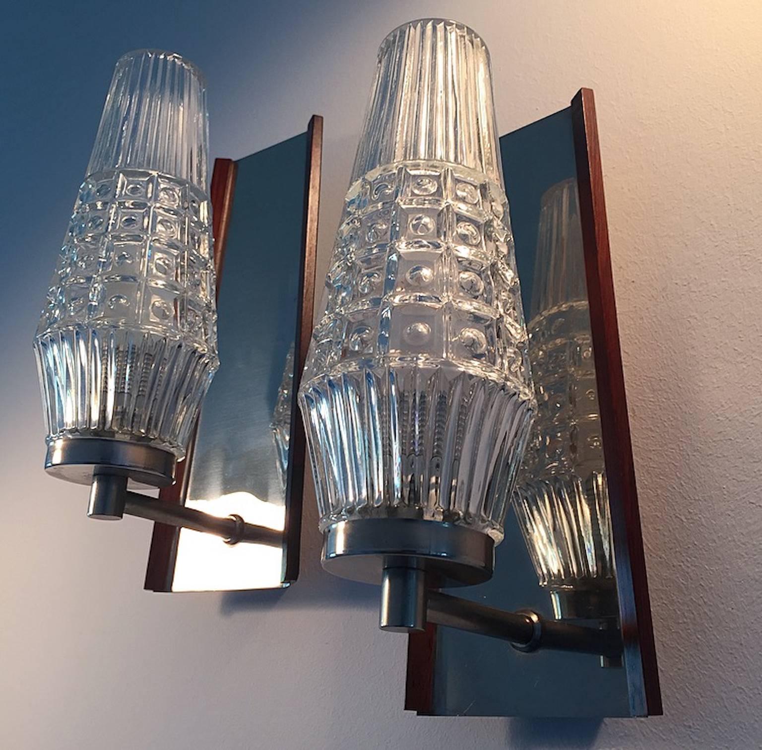 A beautiful set of Danish wall sconces attributed Vitrika and Orrefors glass.

Conical shaped base which reflexes the light as in a mirror. Both sides of the sconces have a thin rosewood molding to finish the amazing lines.

Condition: Close to