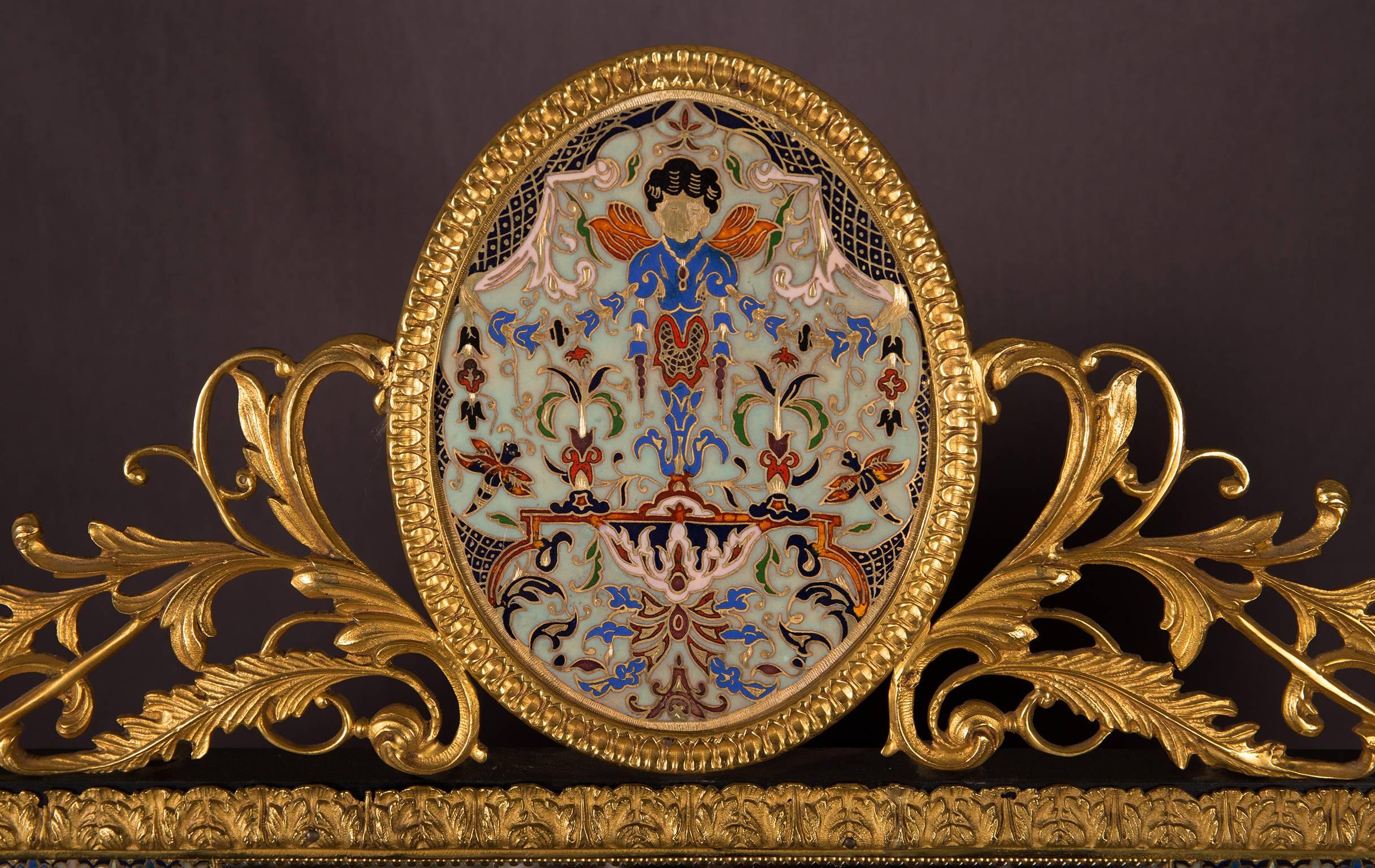 Decorative and unique rectangular wall mirror with gilt brass mounts, on the corners four champlevé enamel fields with floral motifs. Crowned with a champleve enamel oval set within gilt brass mounts and ornaments. 
Manufactured in France in the