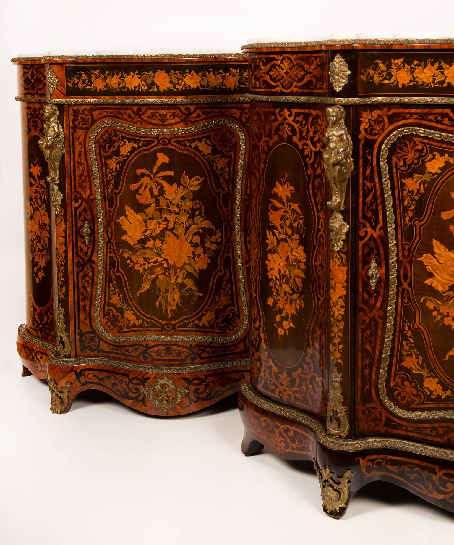 A genuine pair of meubles d´appui, with reverse inlay of floral scrolls and flower marquetry of profusely colored and stained woods. Strapwork borders and bronze ornaments of sitting figures on the corners.
The interior of each cabinet has two